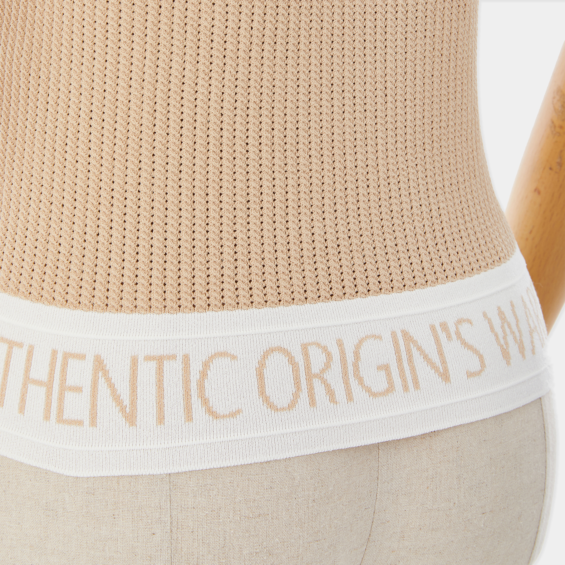 Beige tank top with brand text on a white background