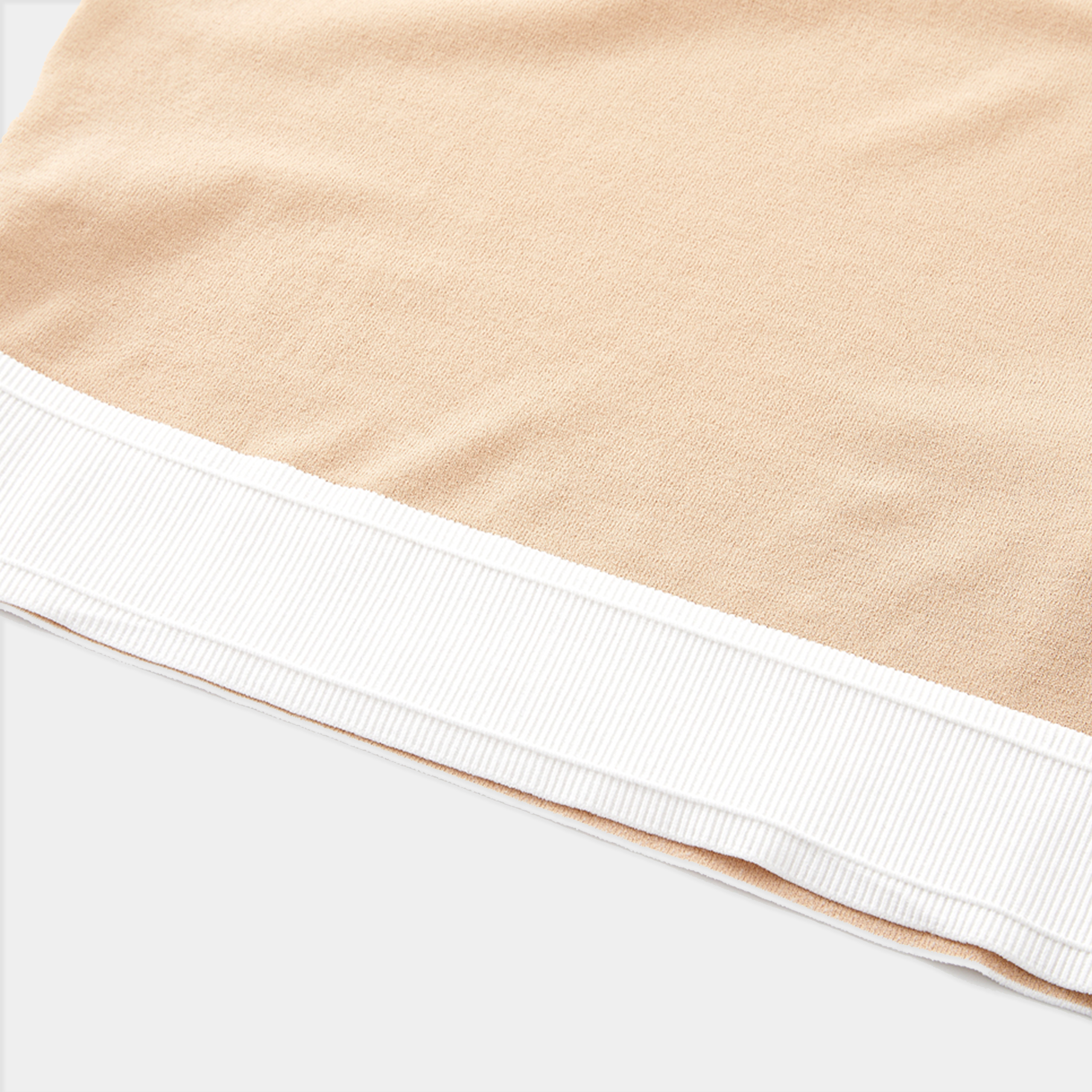 Close-up of beige fabric with white trim on a white background