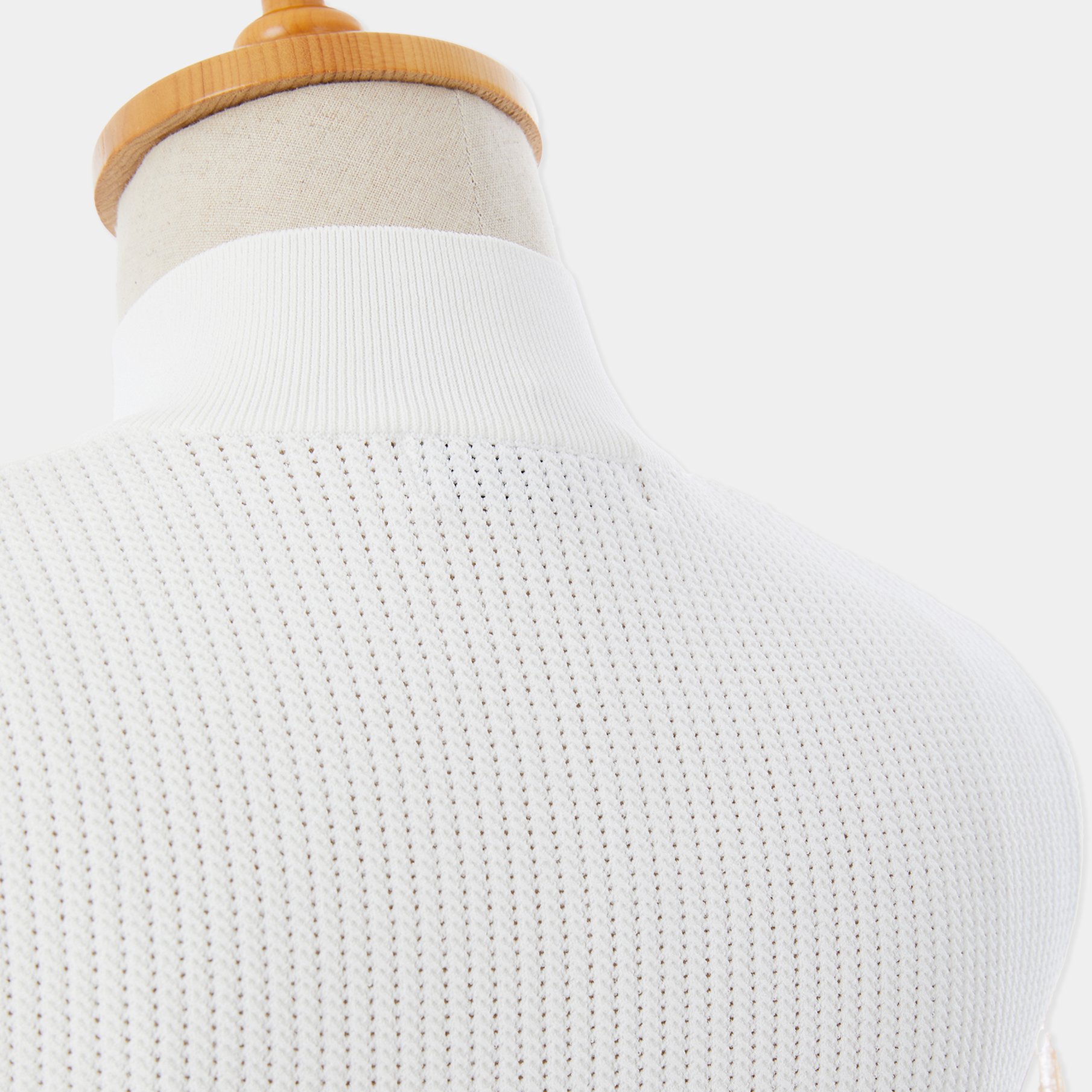 White turtleneck sweater on a mannequin with a plain background