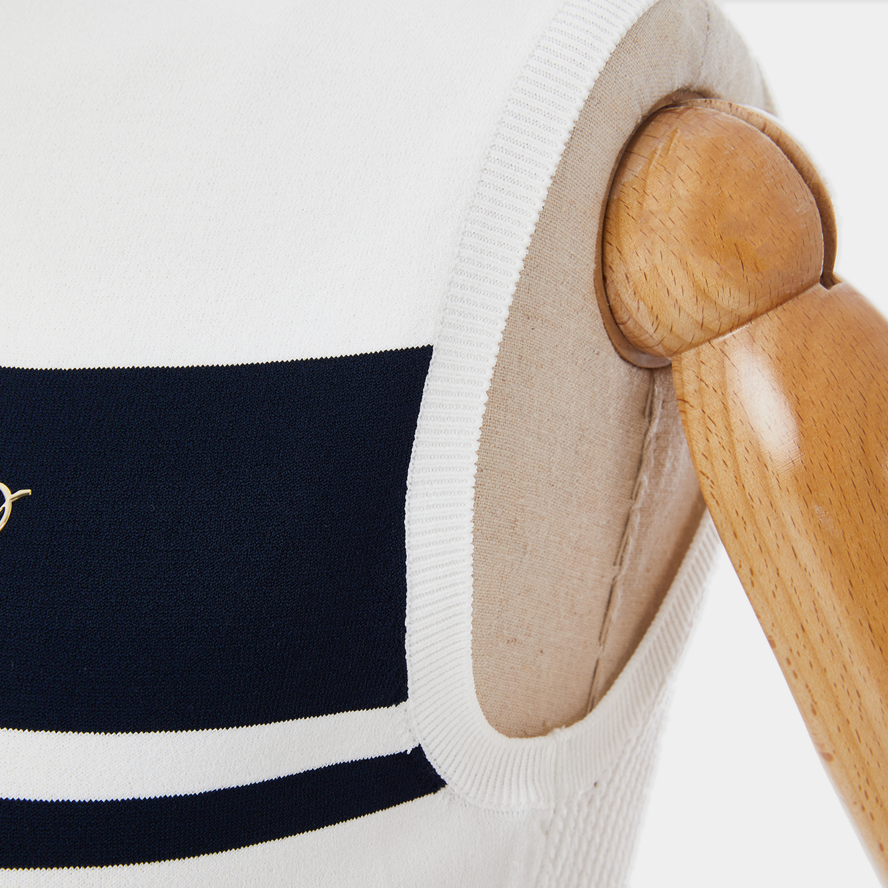 Nautical-themed sweater with navy and white stripes on a wooden hanger against a white background