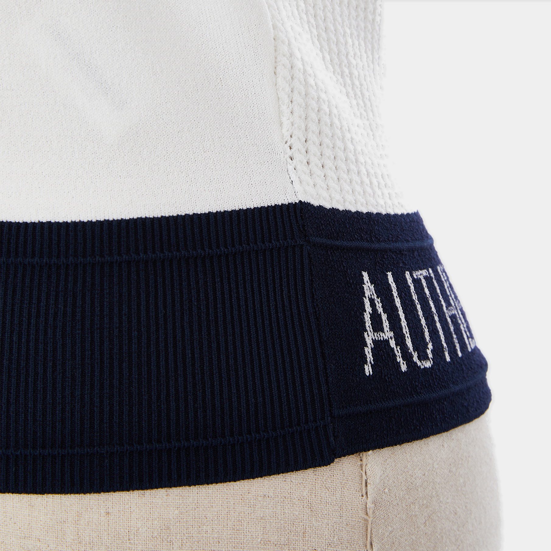 Close-up of a garment with 'AUTHENTIC ORIGIN'S WARDROBE' branding on a neutral background