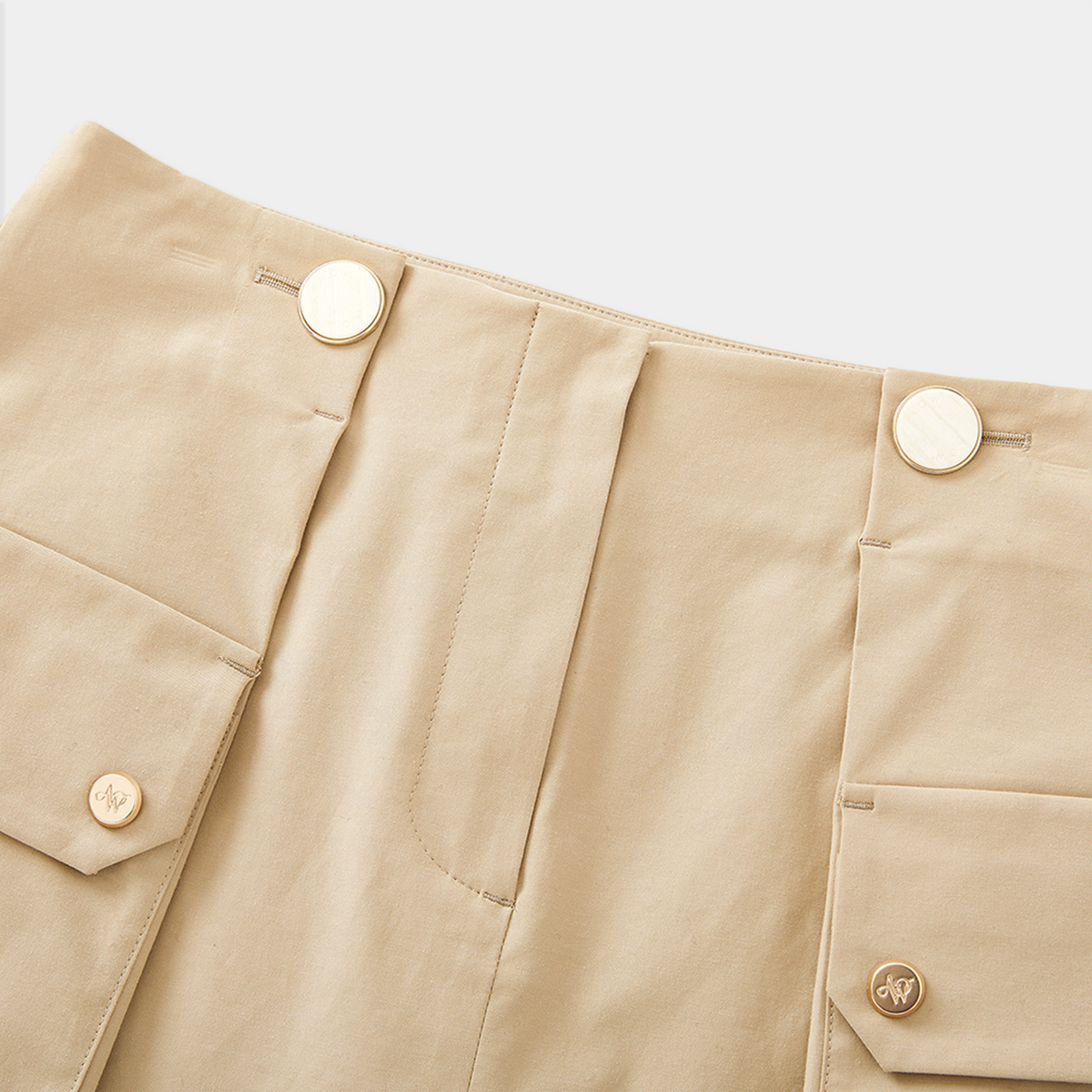 Close-up of beige skirt with gold buttons on a light gray background