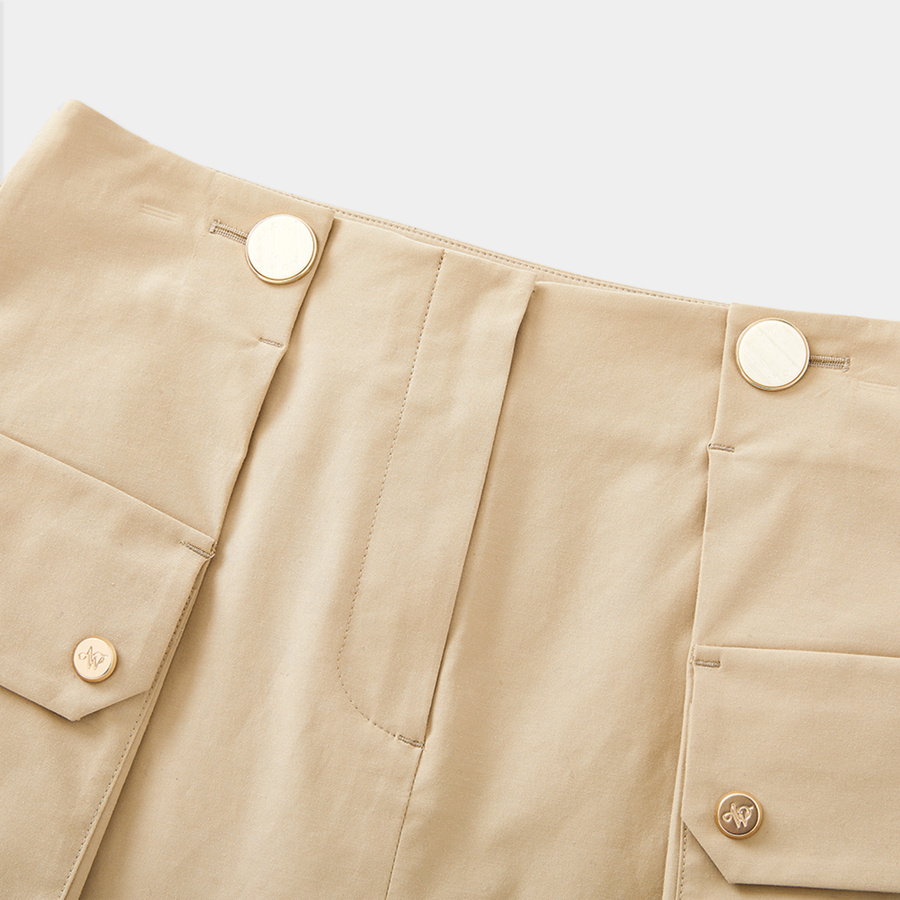 Close-up of beige skirt with gold buttons on a light gray background