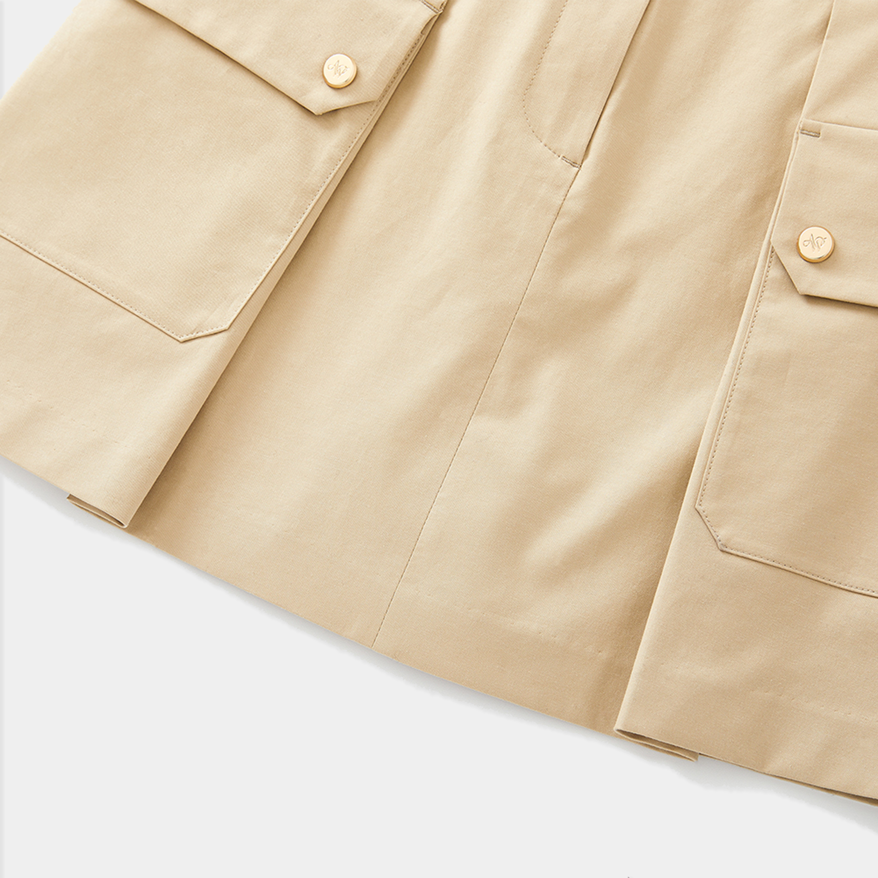 Close-up of a beige skirt with button details on a light background