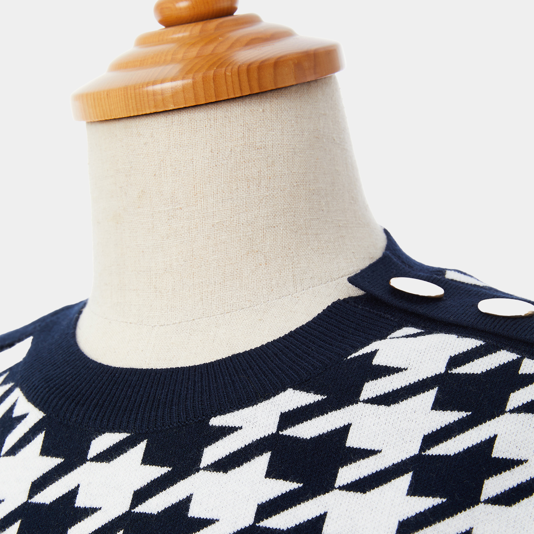 Navy blue and white patterned sweater on a mannequin with a wooden head.
