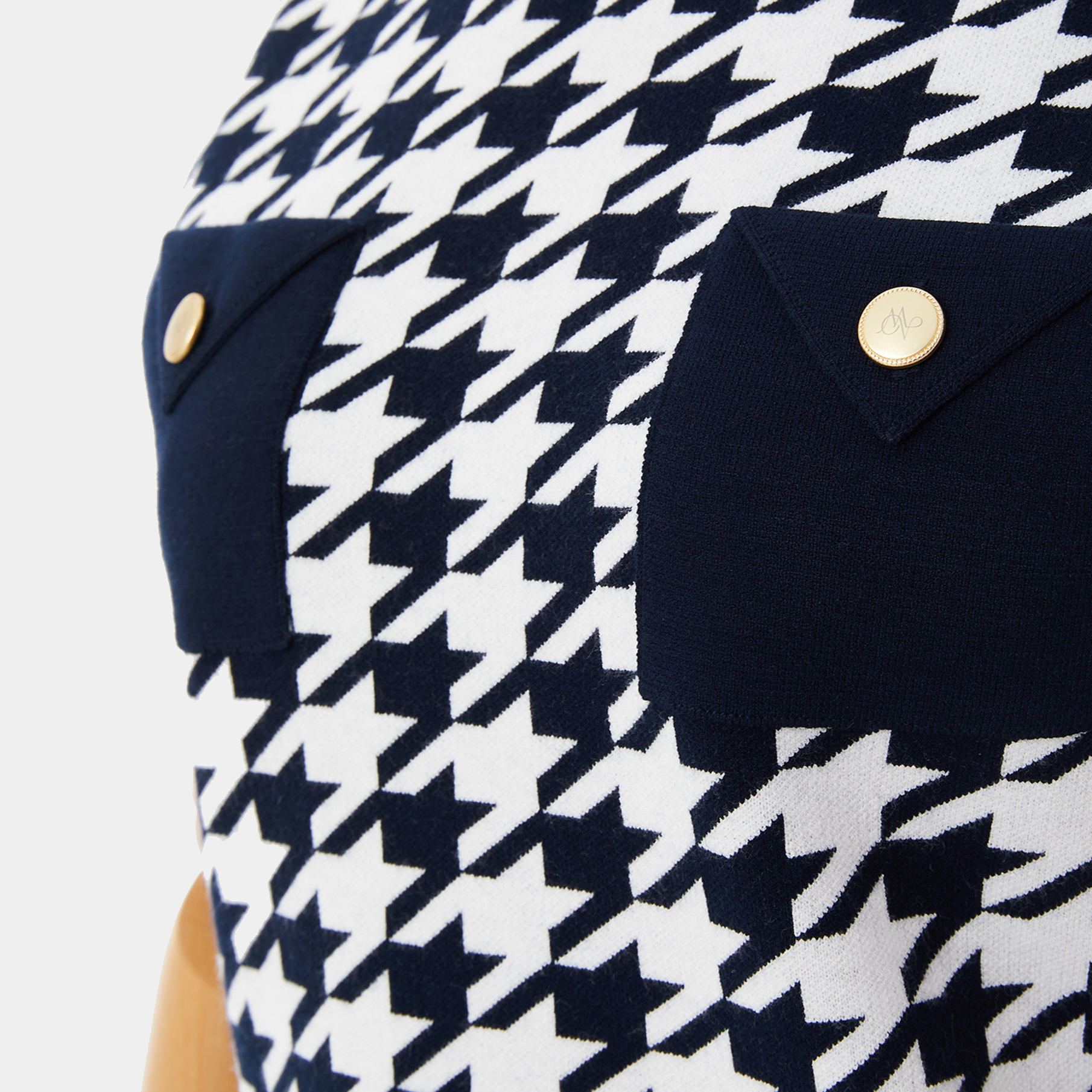 Navy and white houndstooth patterned shirt with gold buttons on a light gray background
