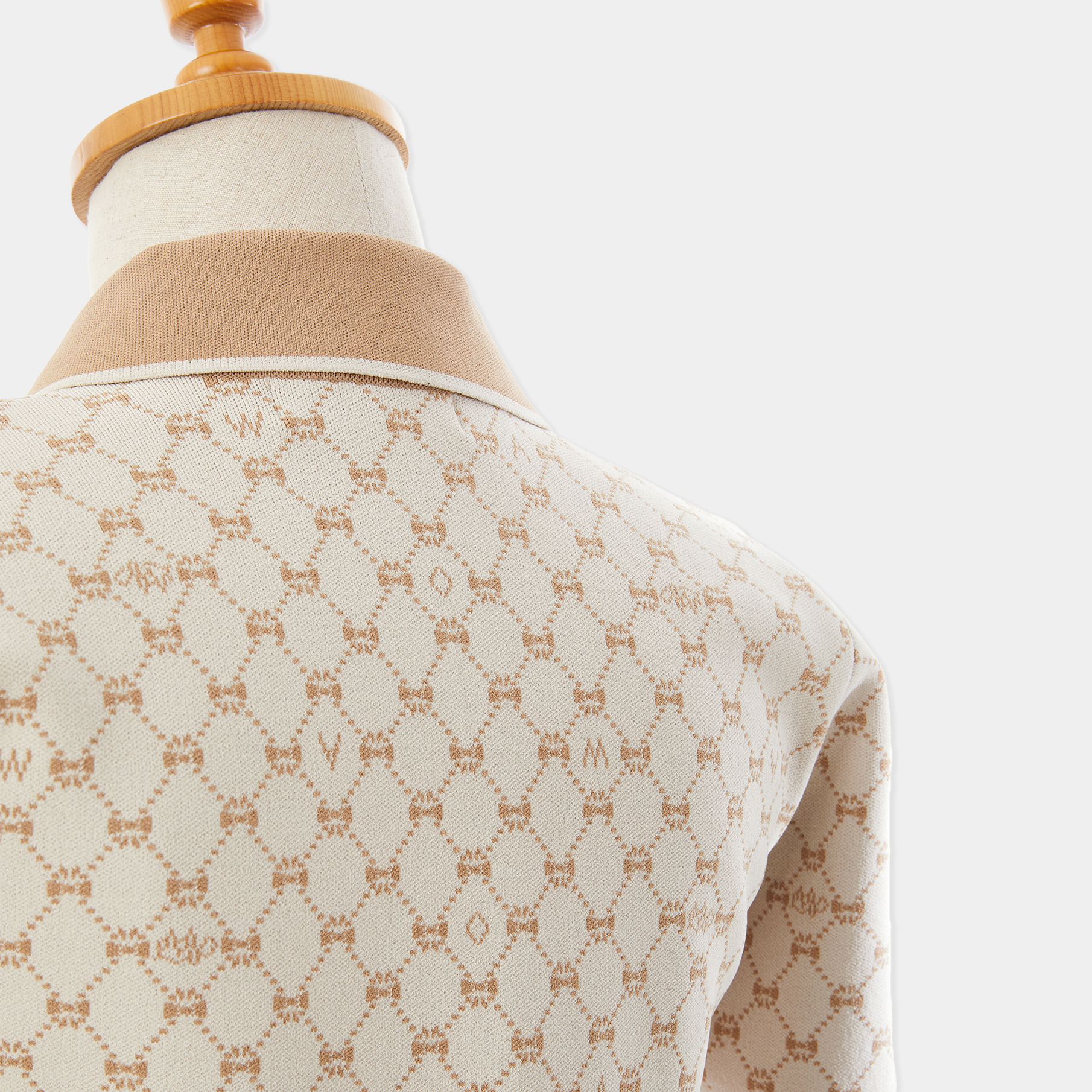 Mannequin wearing a beige patterned garment on a white background