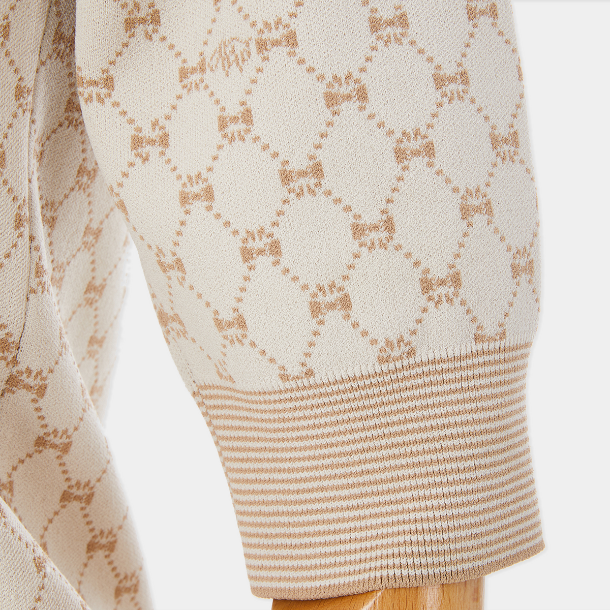 Close-up of a beige sweater with a subtle pattern on a white background