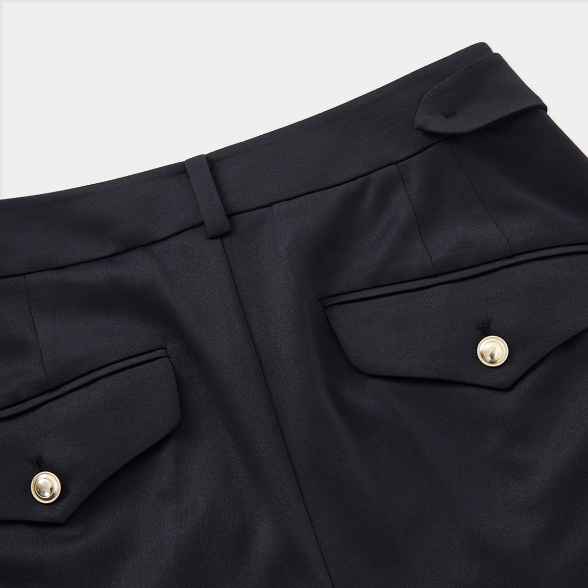 Close-up of black pants with gold buttons on a white background