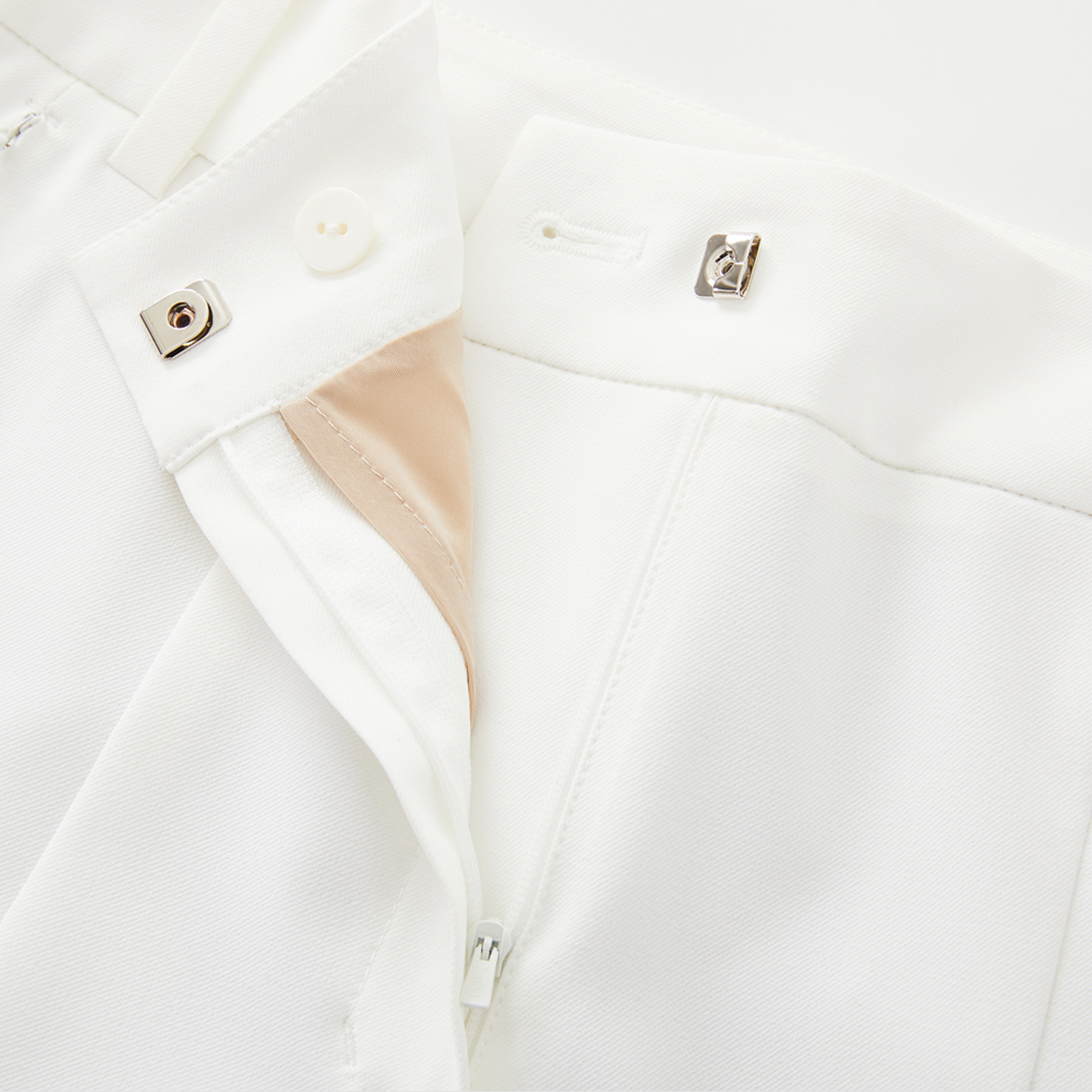 Close-up of white pants with beige lining on a white background