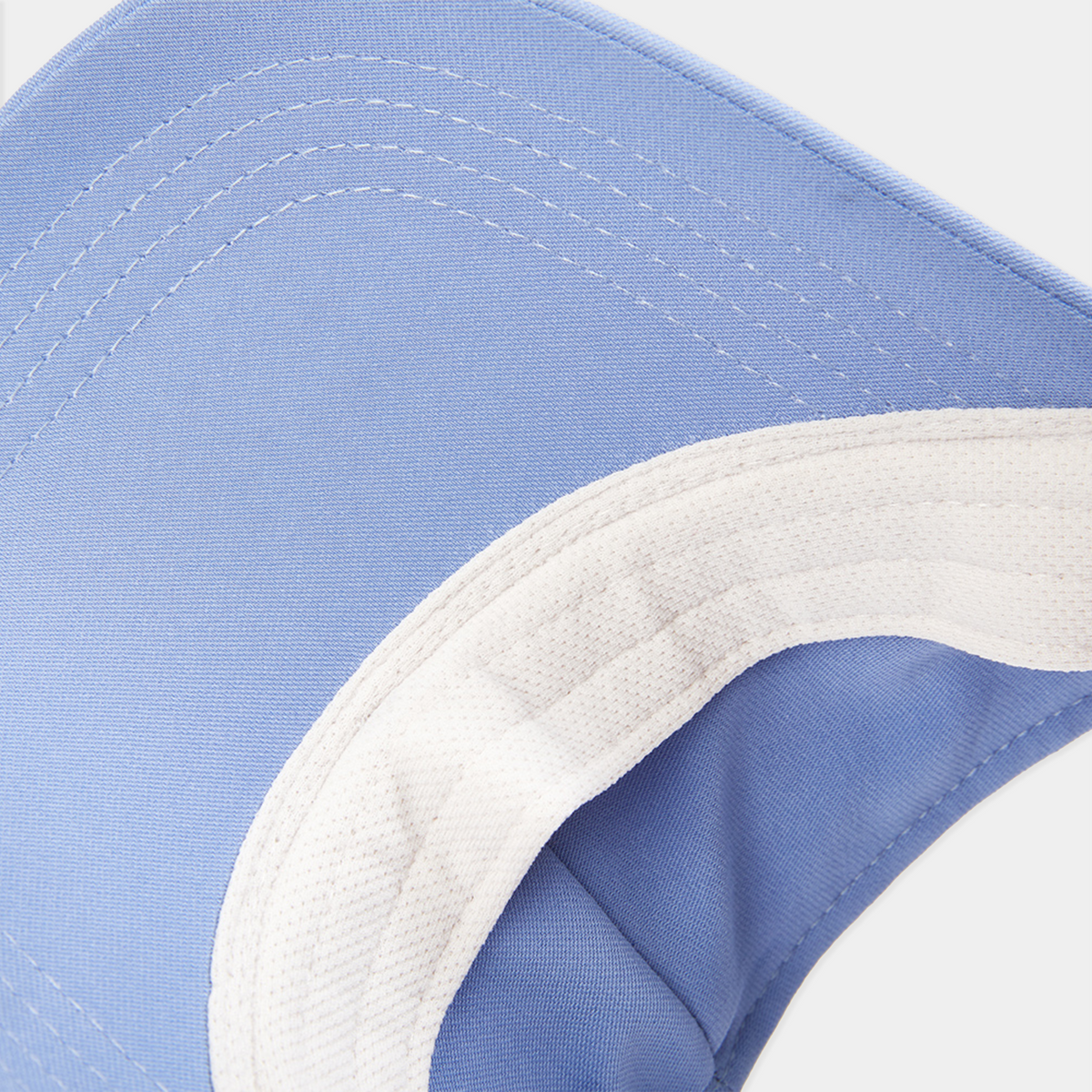Close-up of a blue and white cap with a focus on the brim and stitching.