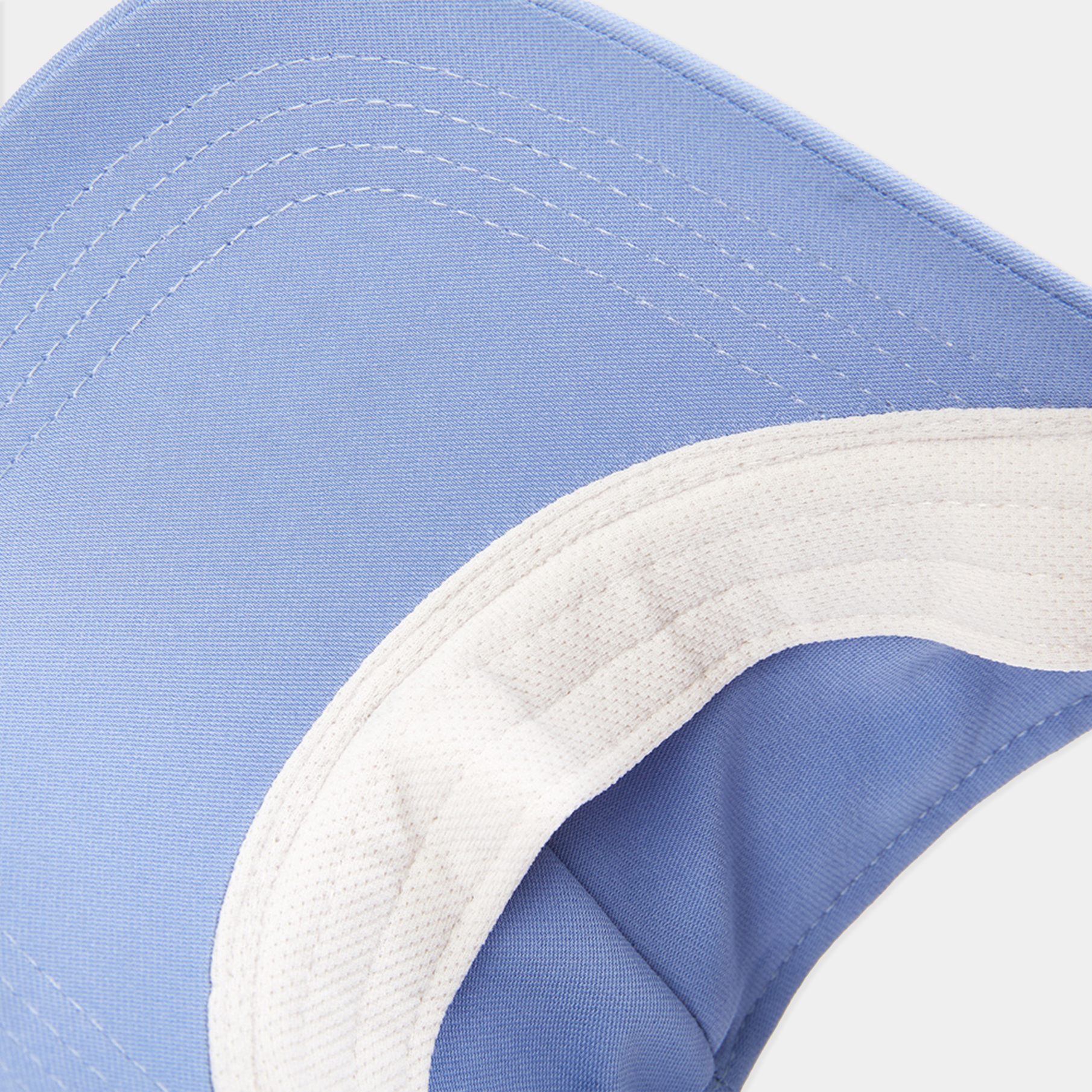 Close-up of a blue and white cap with a focus on the brim and stitching.