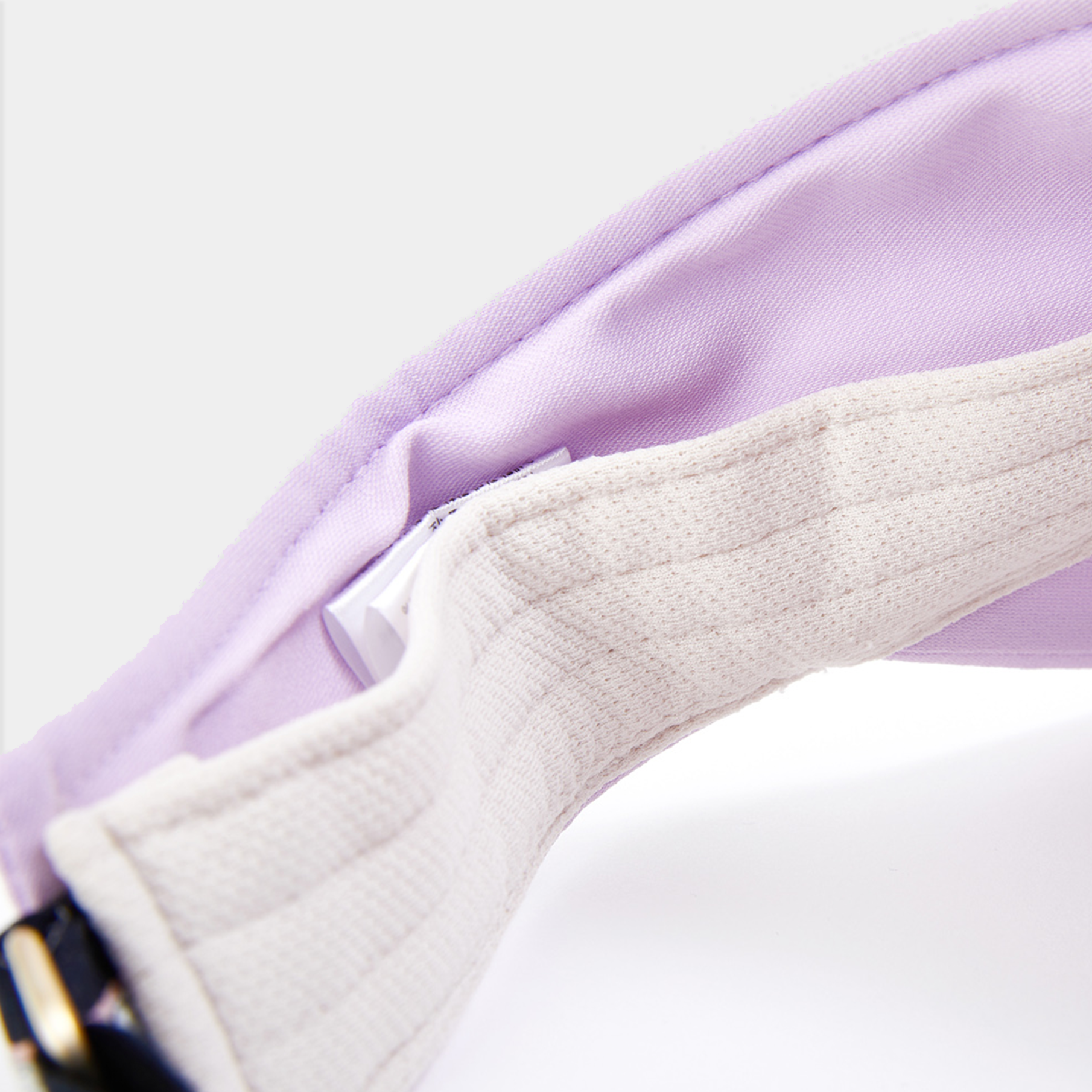 Close-up of a purple visor with a white strap on a light gray background