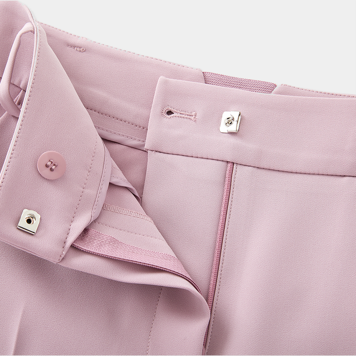 Close-up of a pink garment with buttons and zippers on a light gray background