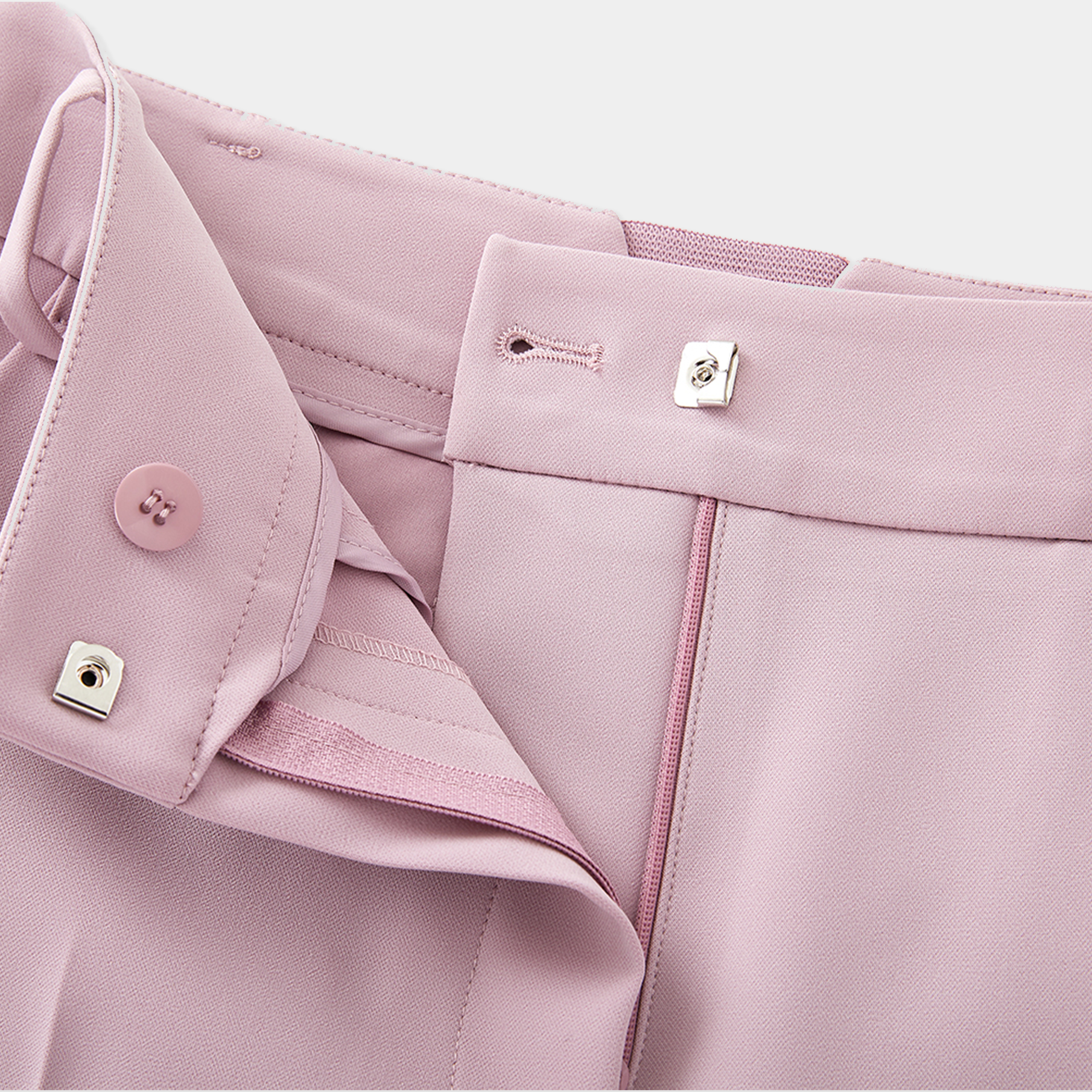 Close-up of a pink garment with buttons and zippers on a light gray background
