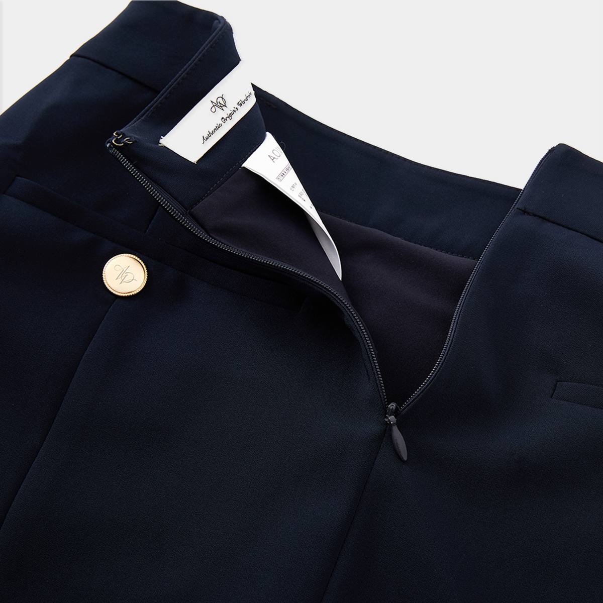 Navy blue skirt with a gold button and white label on a light gray background