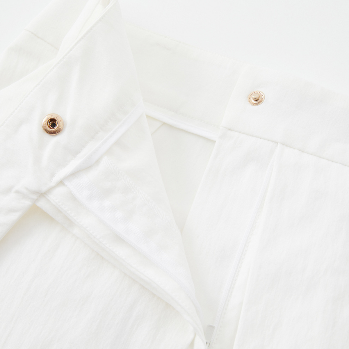 Close-up of a white shirt with button details on a light background