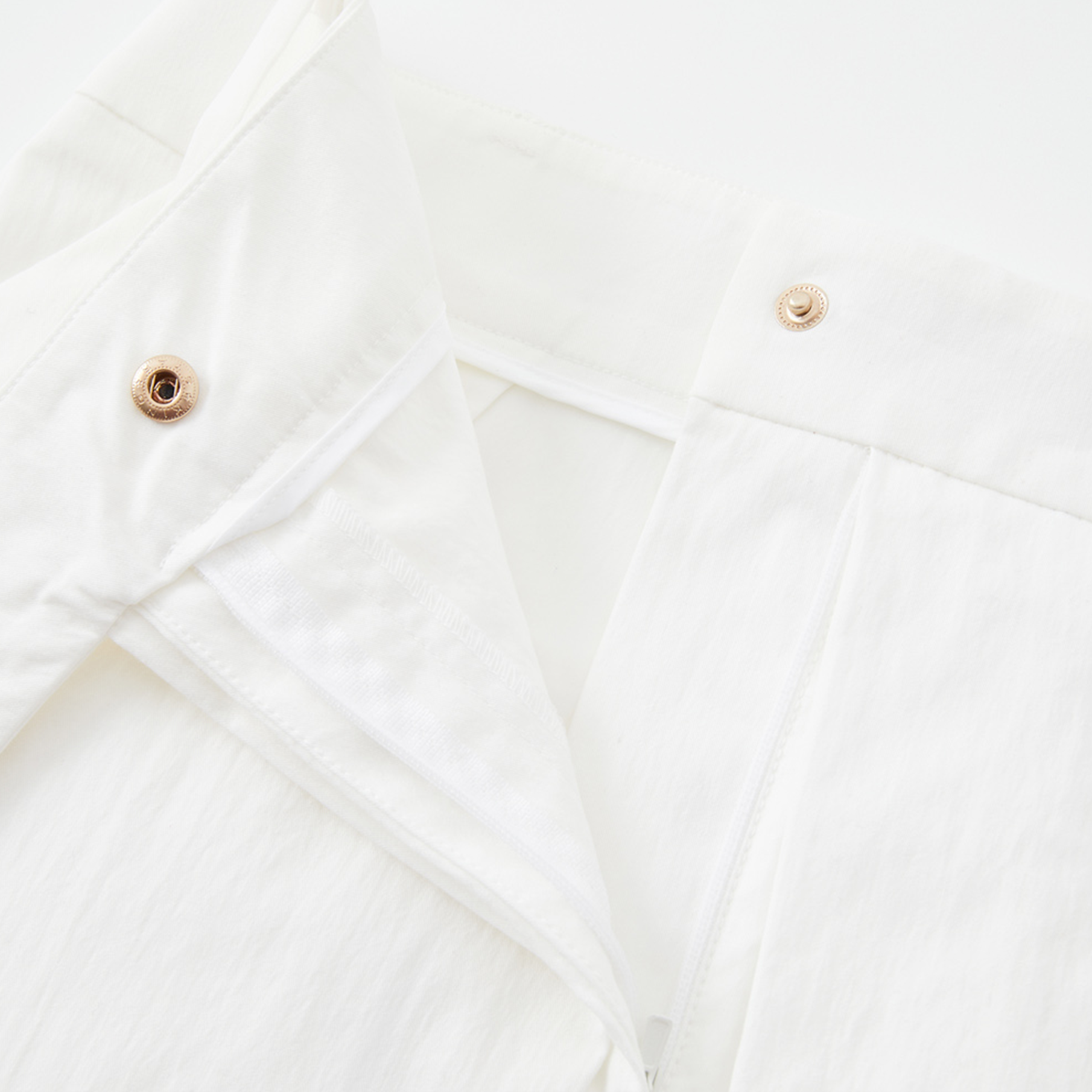 Close-up of a white shirt with button details on a light background