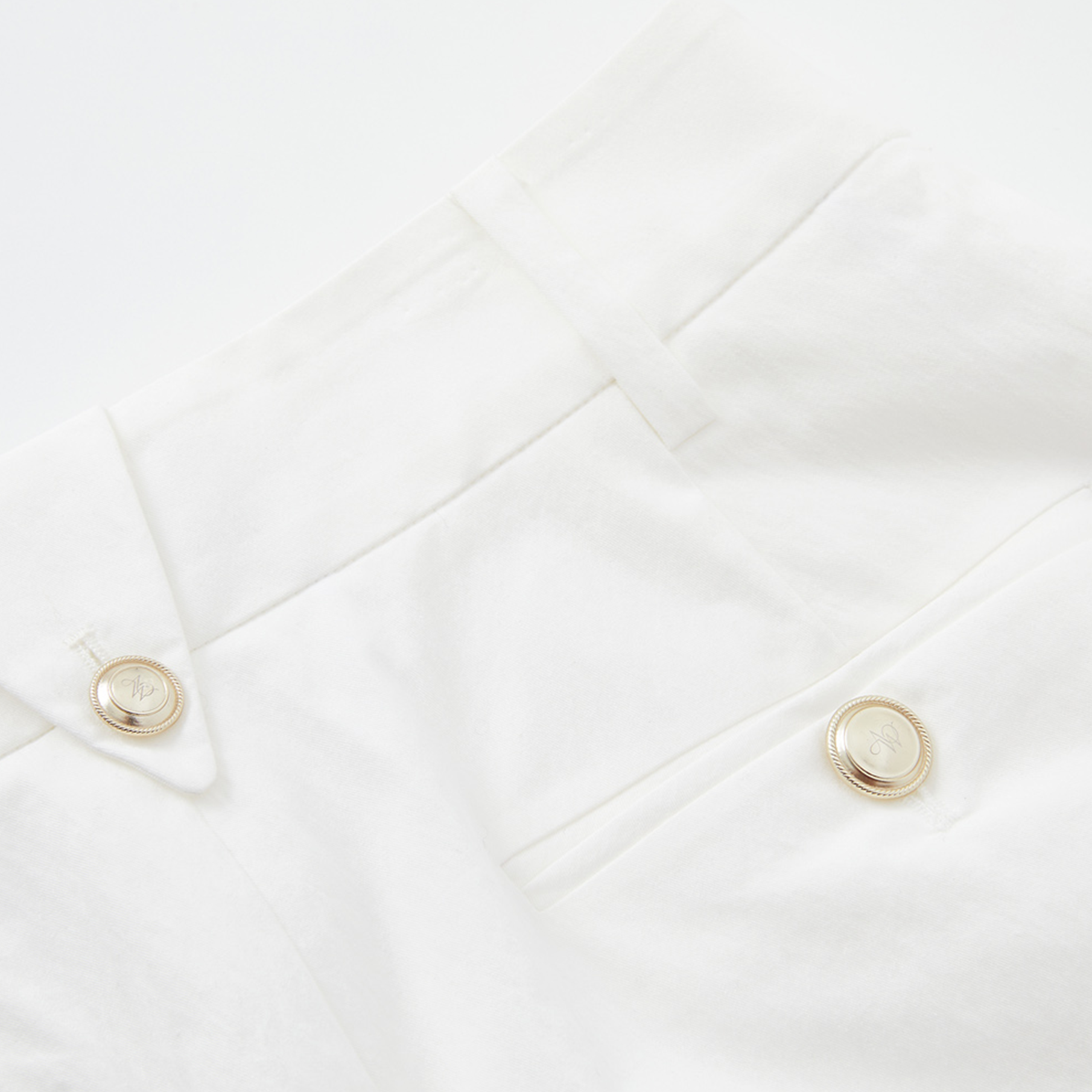 Close-up of a white garment with gold buttons on a white background