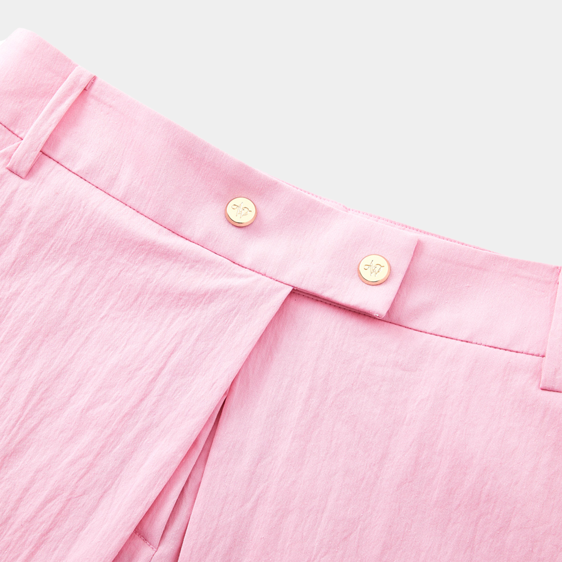 Close-up of pink pants with button details on a light gray background