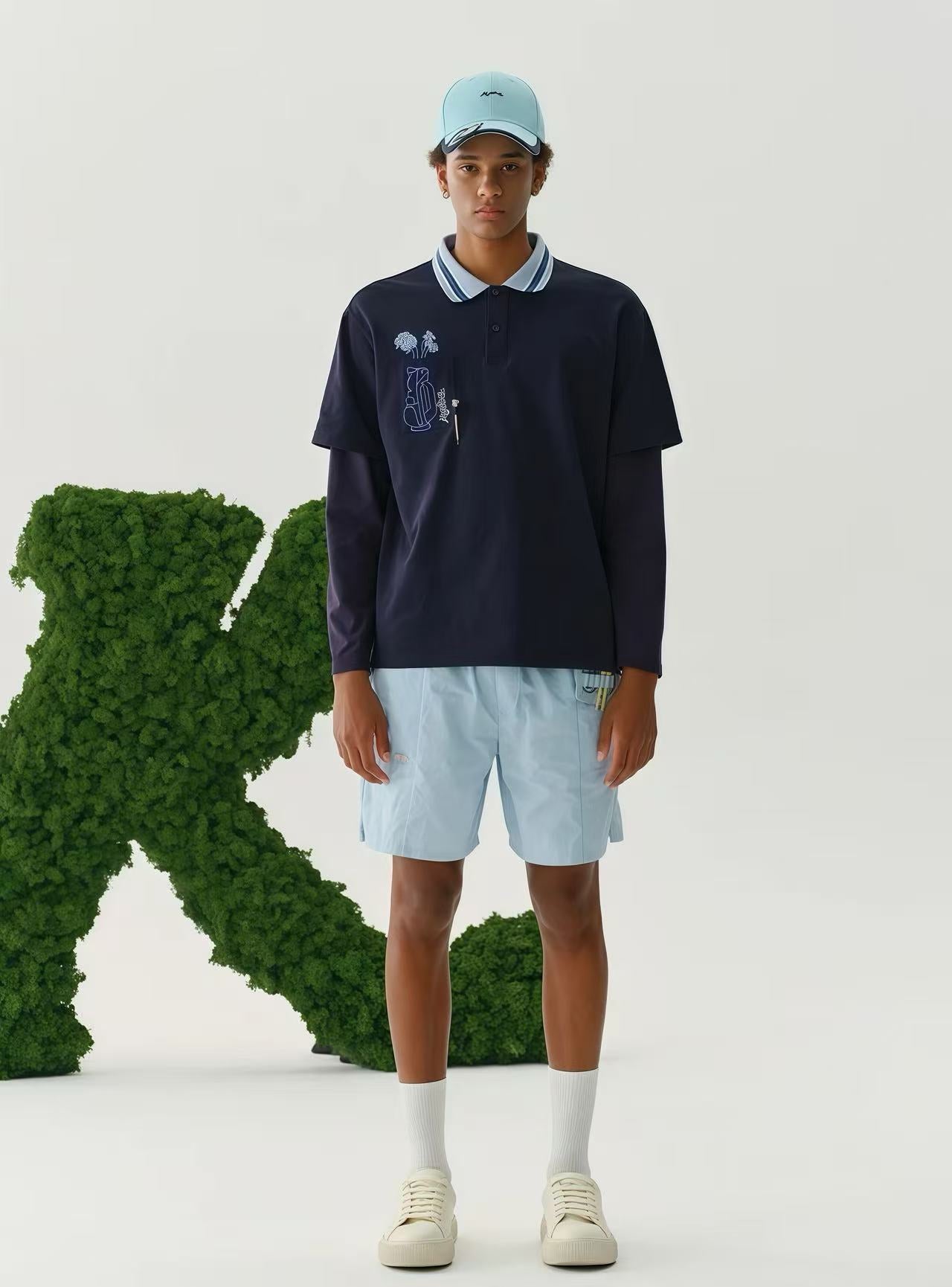 A man wearing a navy polo shirt and a light blue shorts.