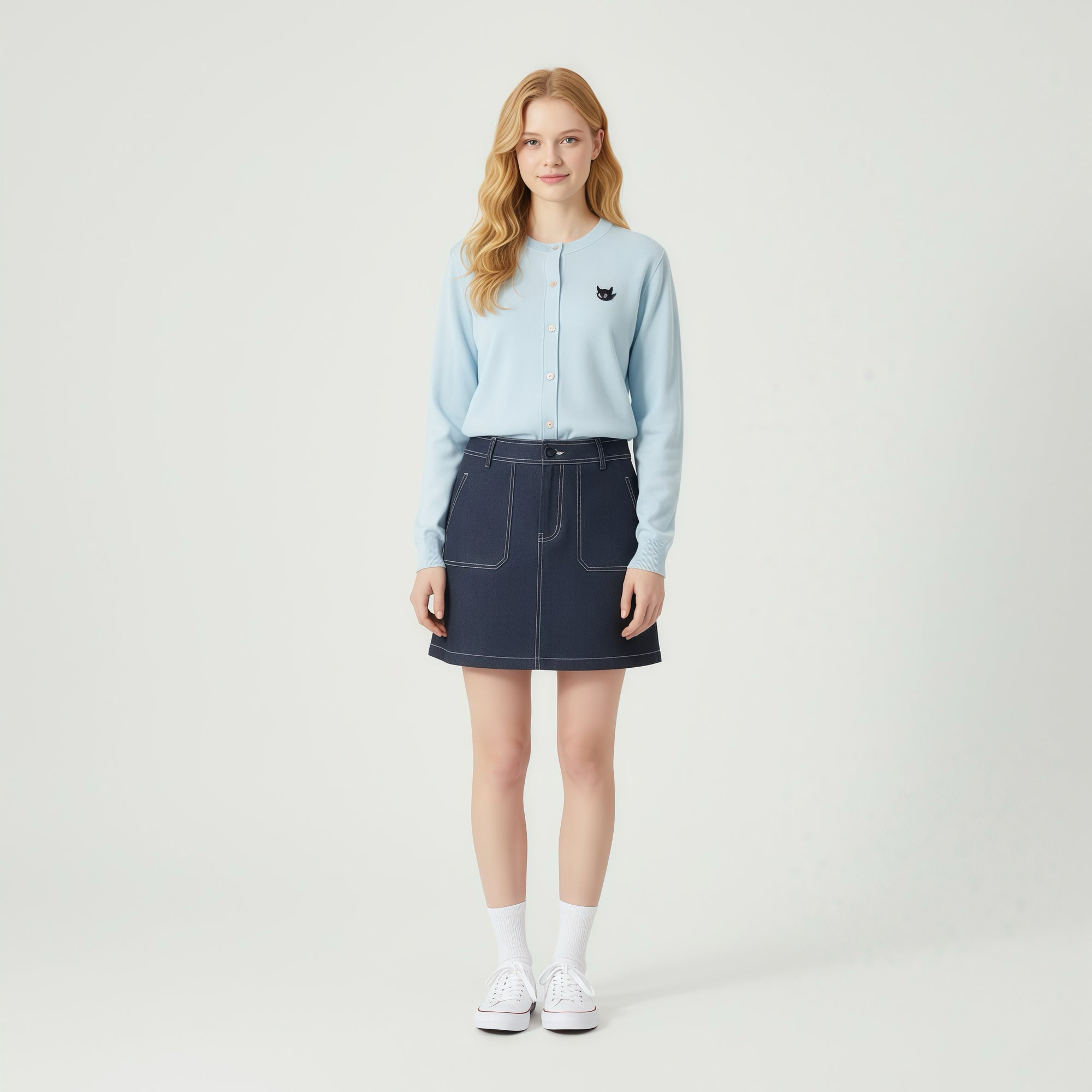 Woman wearing a light blue sweatshirt and dark blue denim skirt on a white background