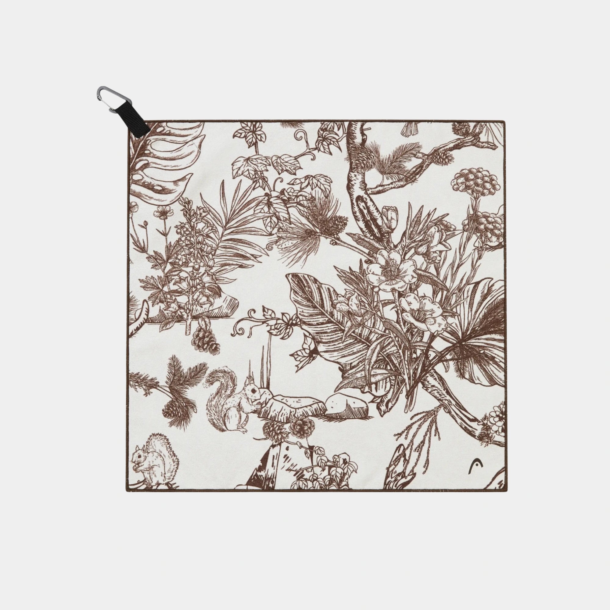 A square fabric towel with a brown botanical and animal toile pattern on a light beige background, featuring a black carabiner clip at the top left, shown against a light gray background.