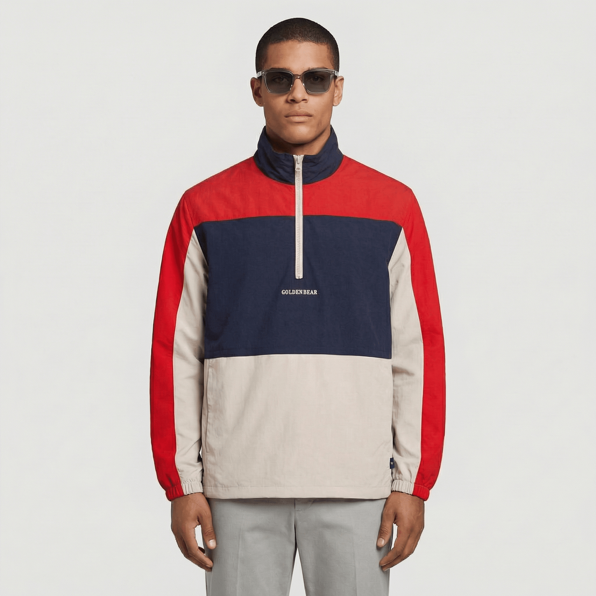 Man wearing a red, blue, and beige color-blocked pullover with 'GOLDEN BEAR' branding on a light gray background.