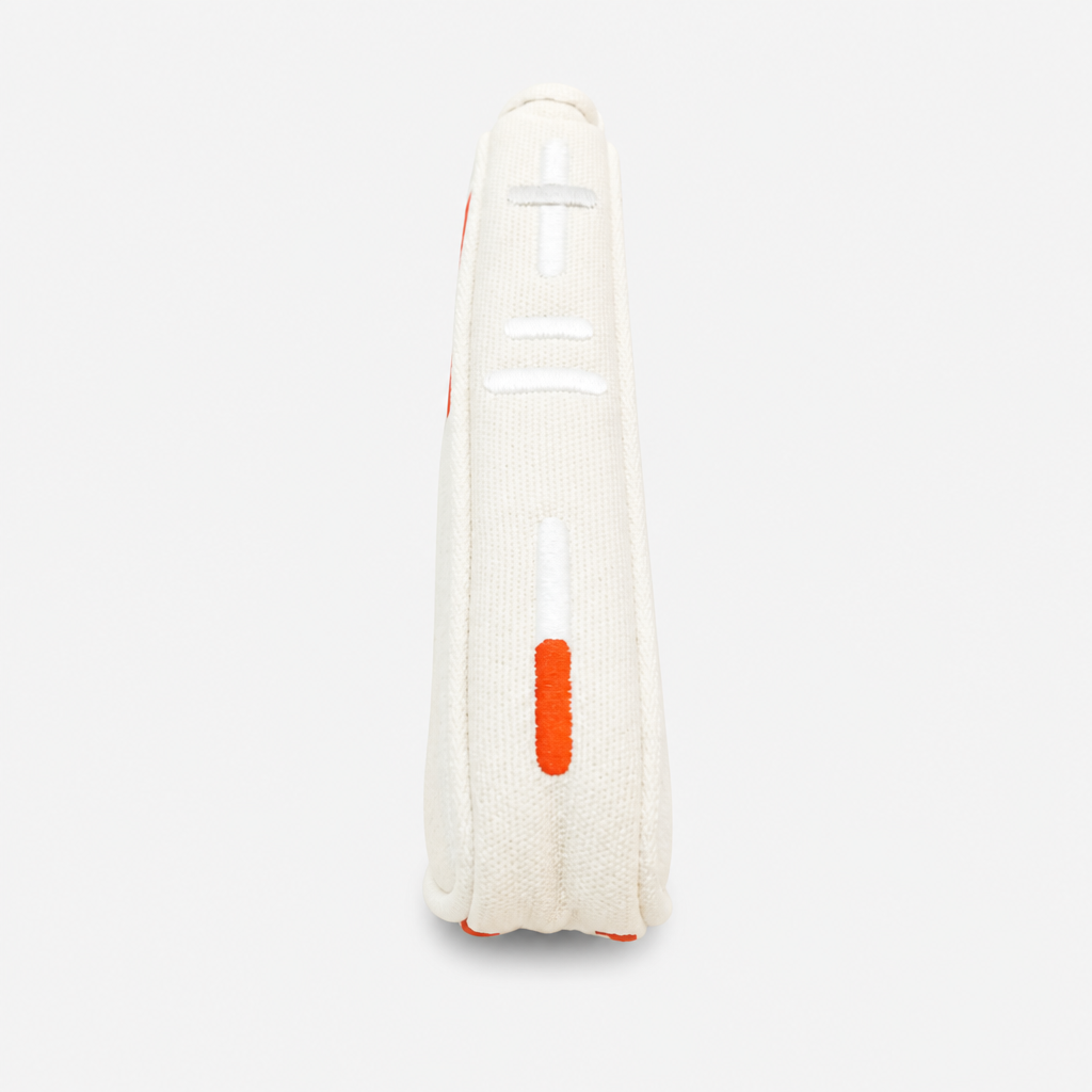 A close-up side view of a white blade putter cover with orange and white embroidered details, set against a light gray background.