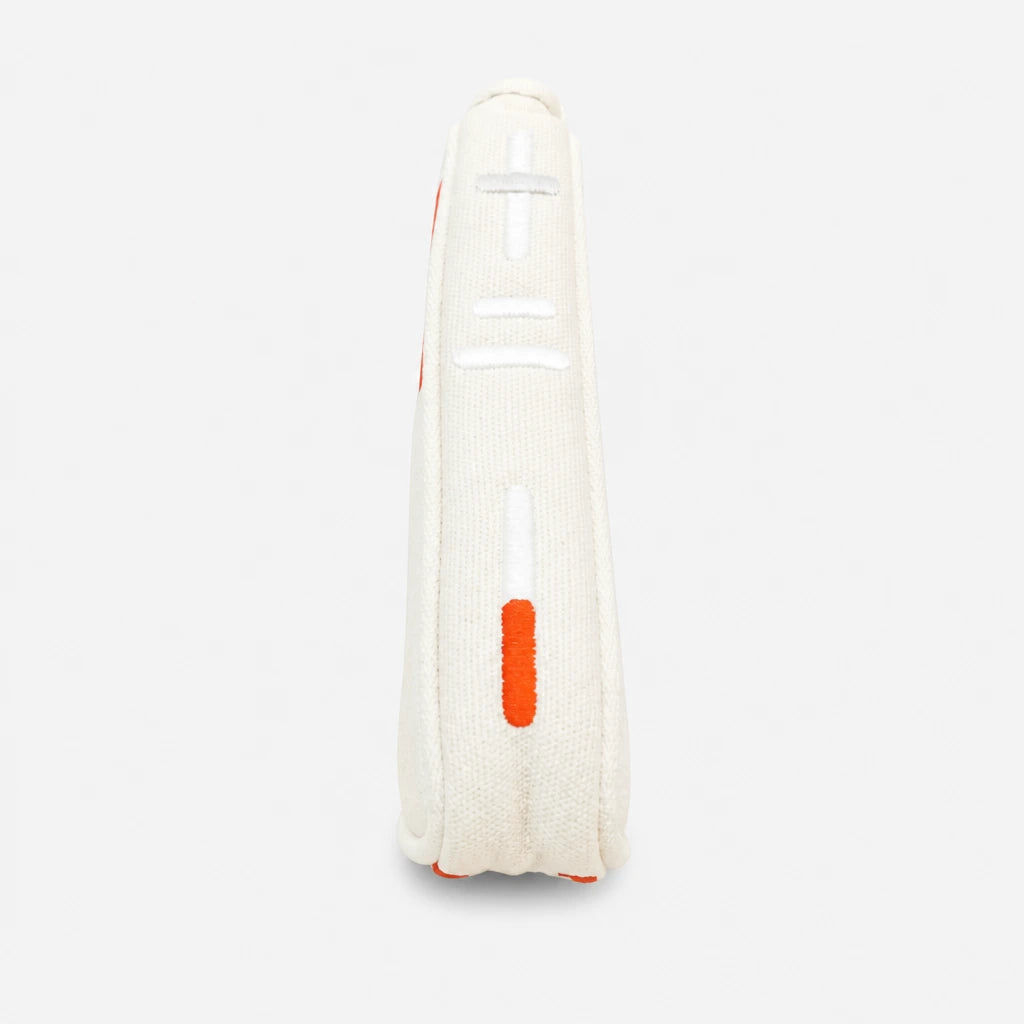 A close-up side view of a white blade putter cover with orange and white embroidered details, set against a light gray background.