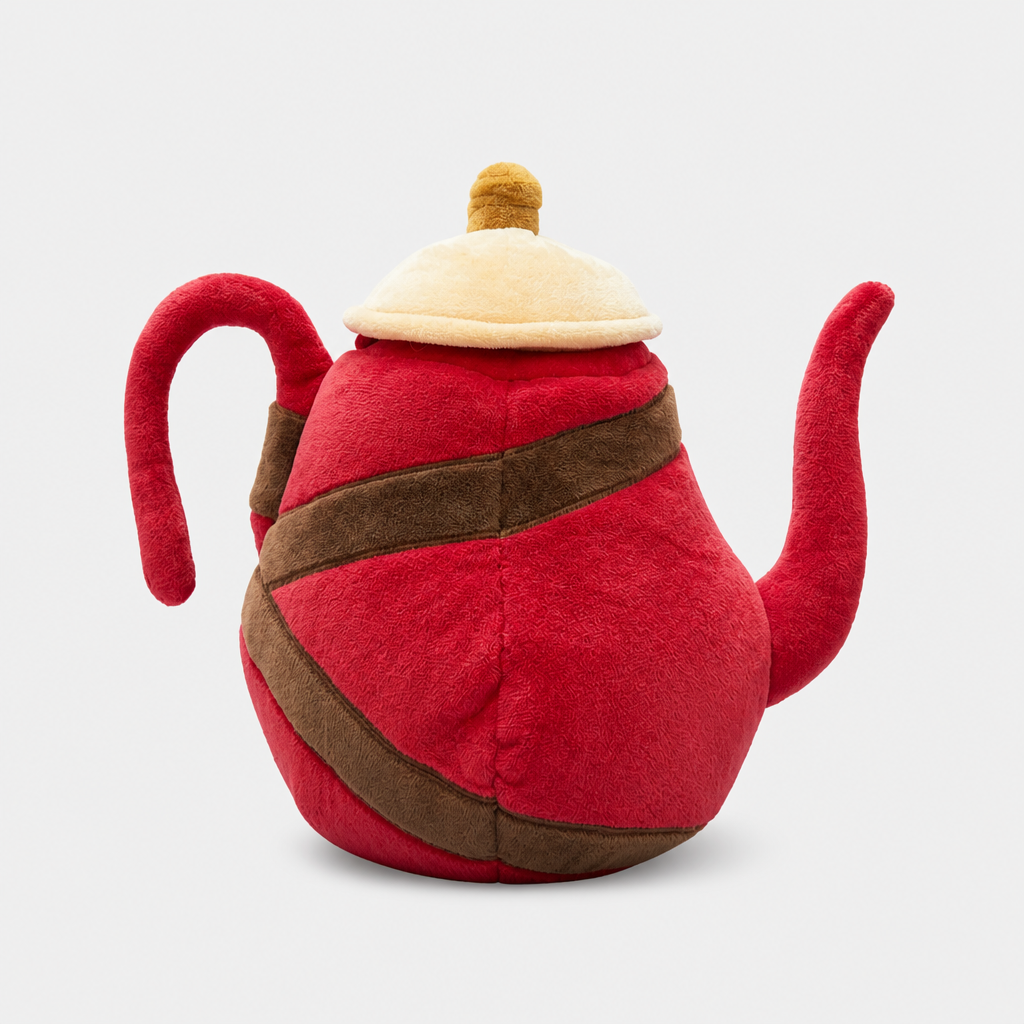 A plush toy teapot head cover with a red body, brown strap details, and a cream-colored lid, photographed against a light gray background.