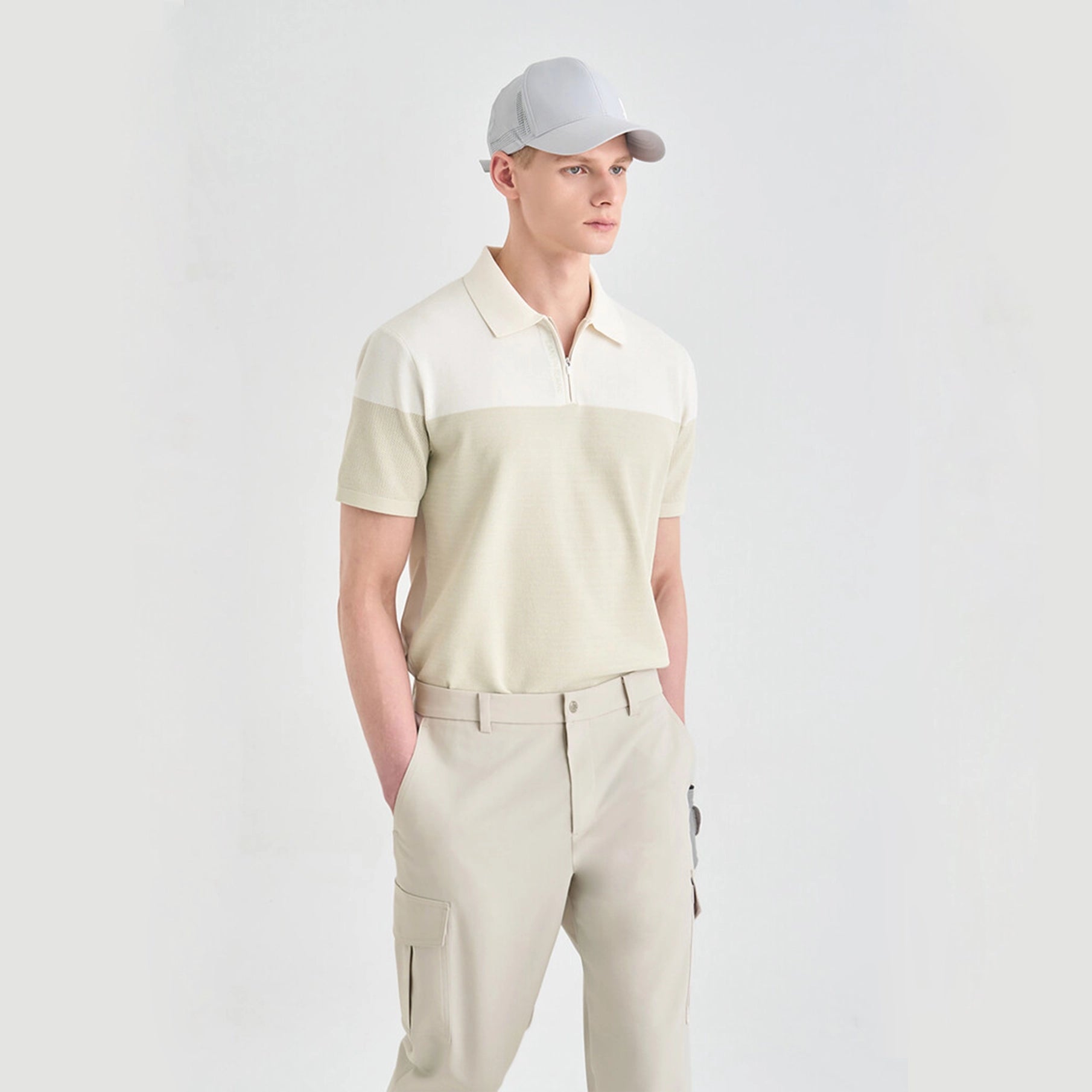 Man wearing a two-tone polo shirt and beige pants on a light gray background