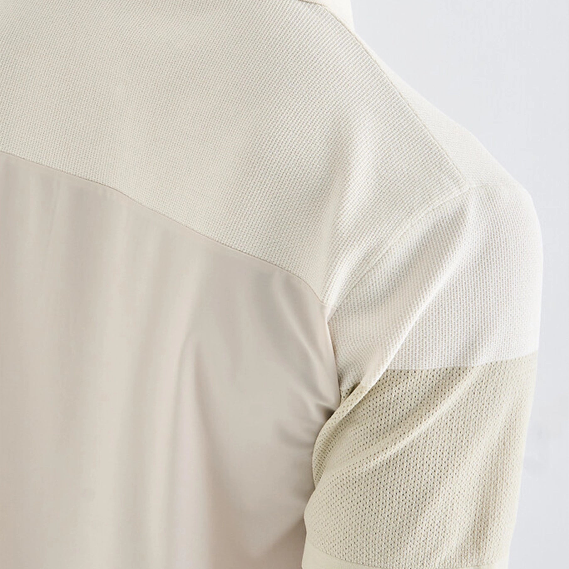Close-up of a beige polo with a textured pattern on a light gray background