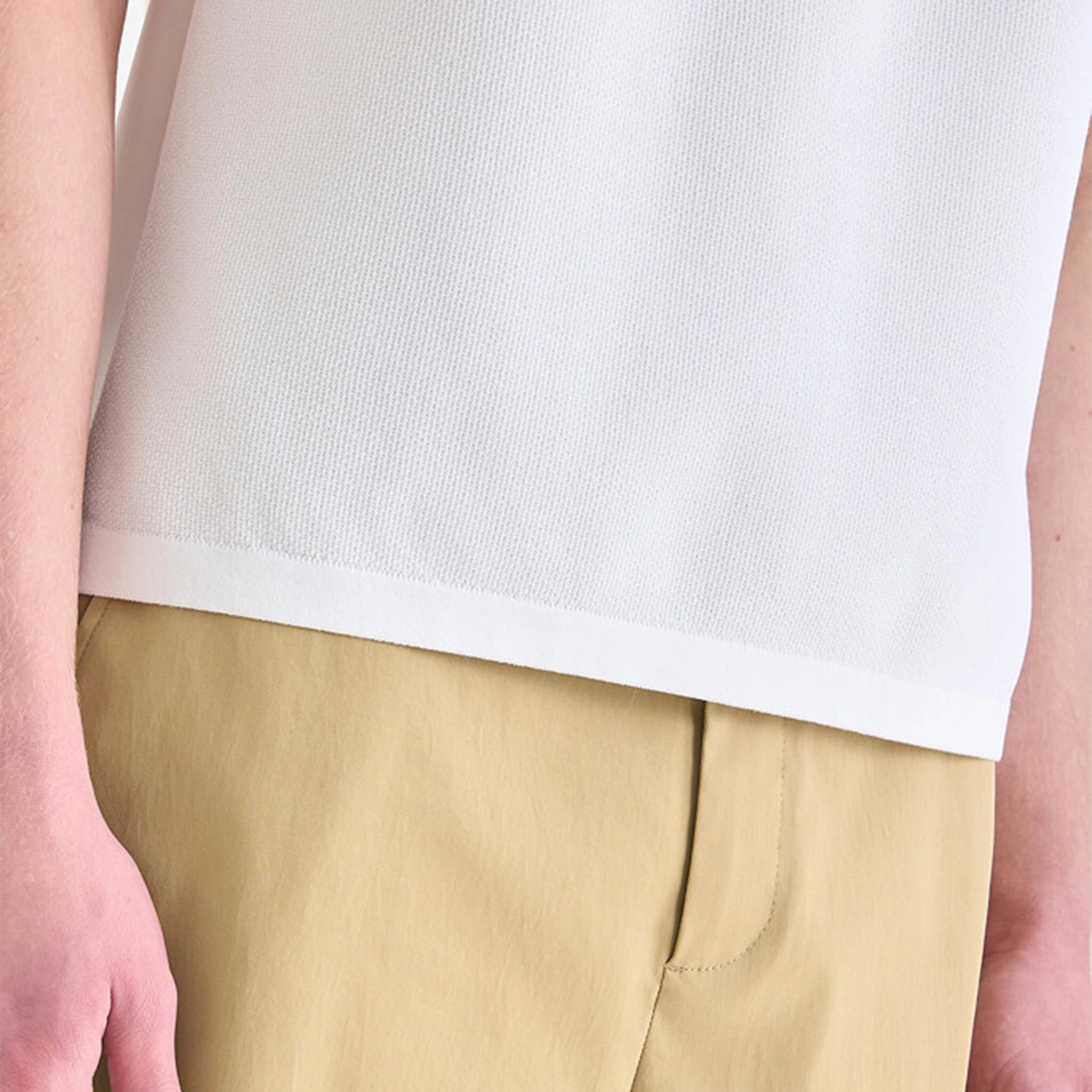 Person wearing a white top and beige pants