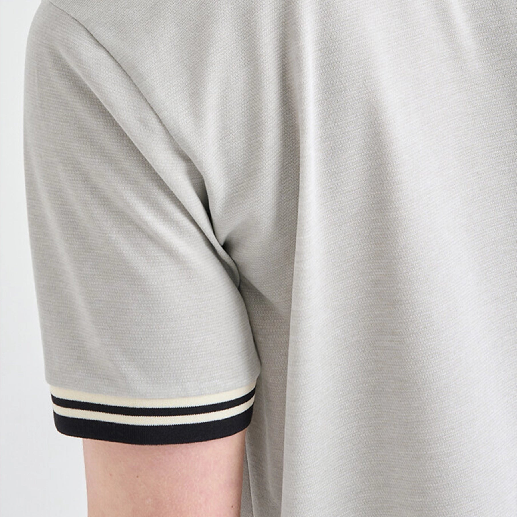 Close-up of a gray shirt with black and white trim on a plain background