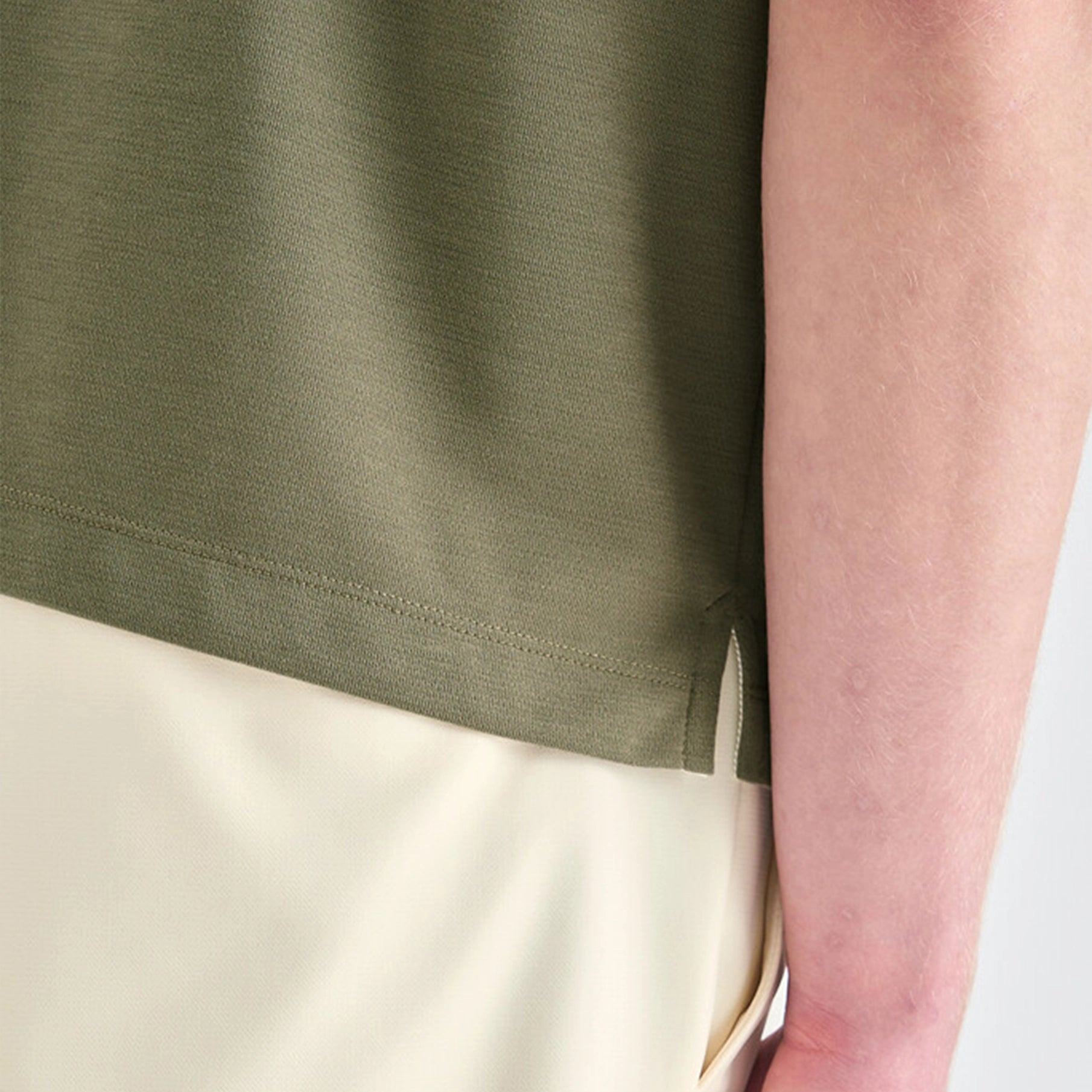 Close-up of a person wearing a green shirt and beige pants.