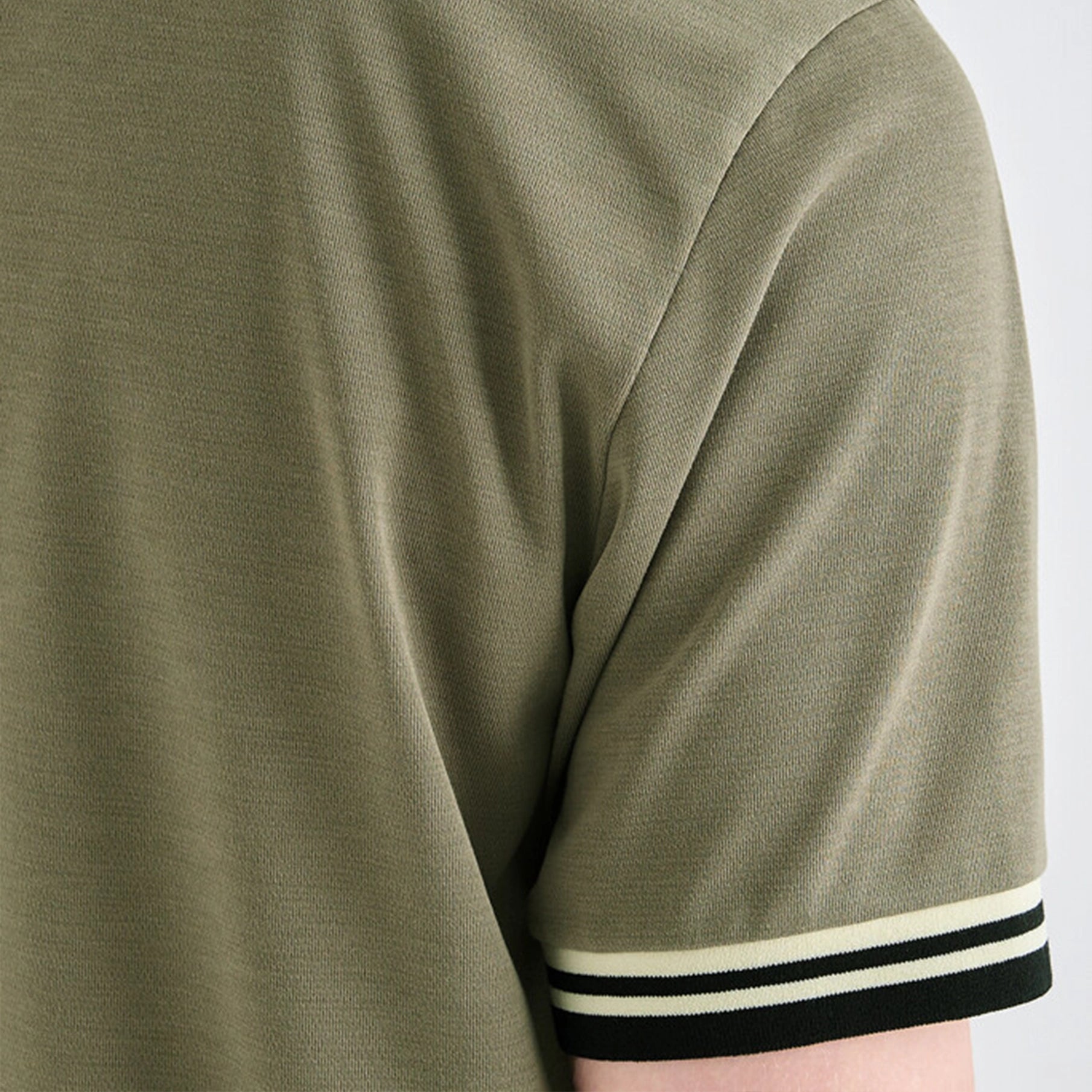Close-up of a green t-shirt with striped cuffs on a white background