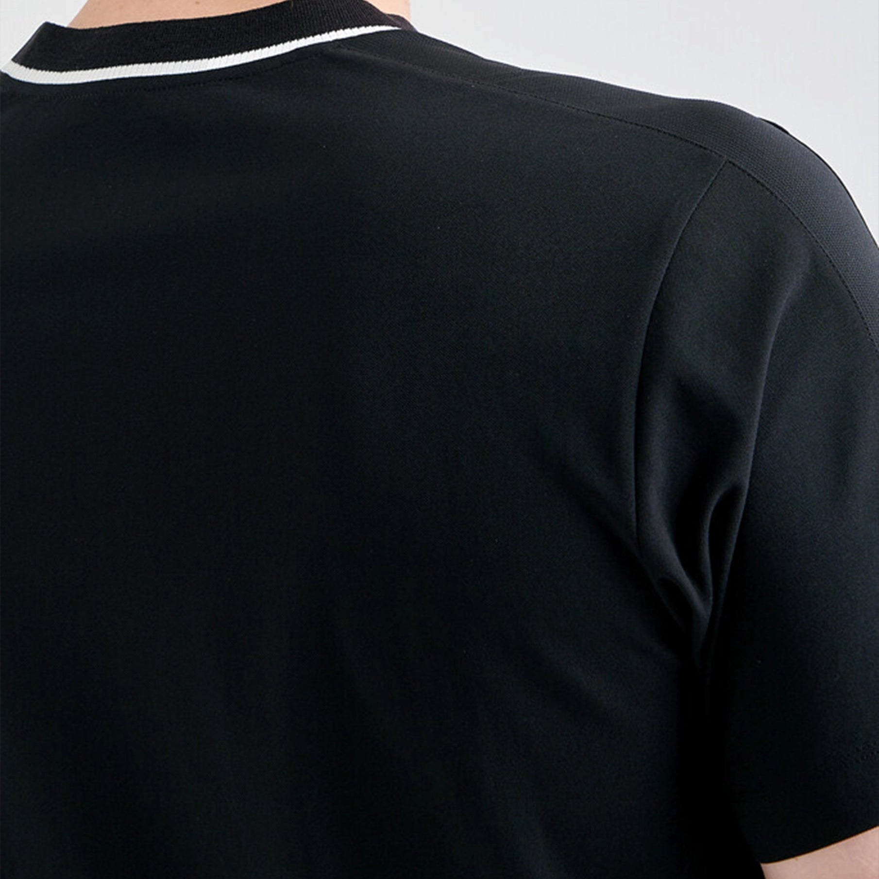 Black t-shirt with white trim on a plain background