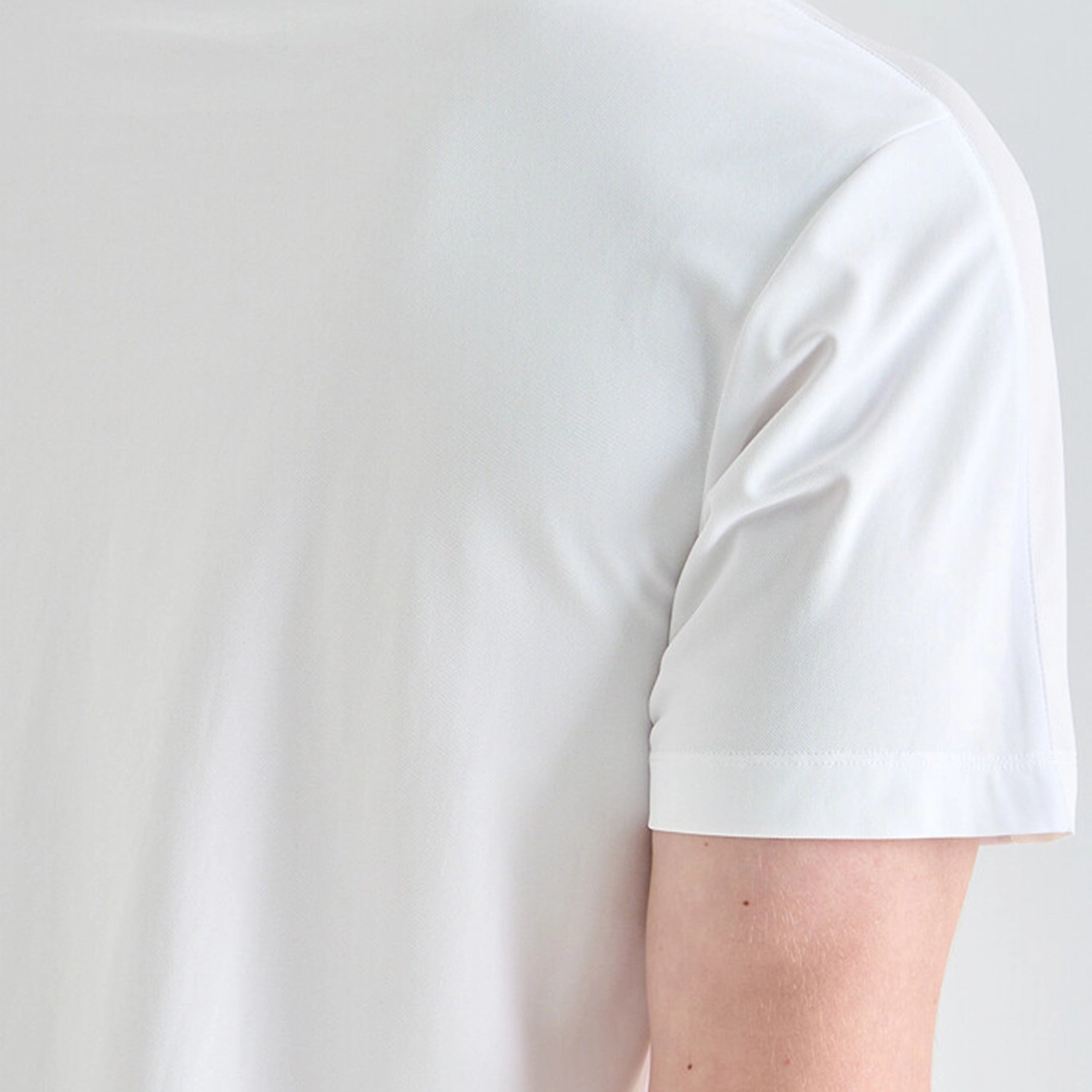 White t-shirt worn by a person on a light gray background
