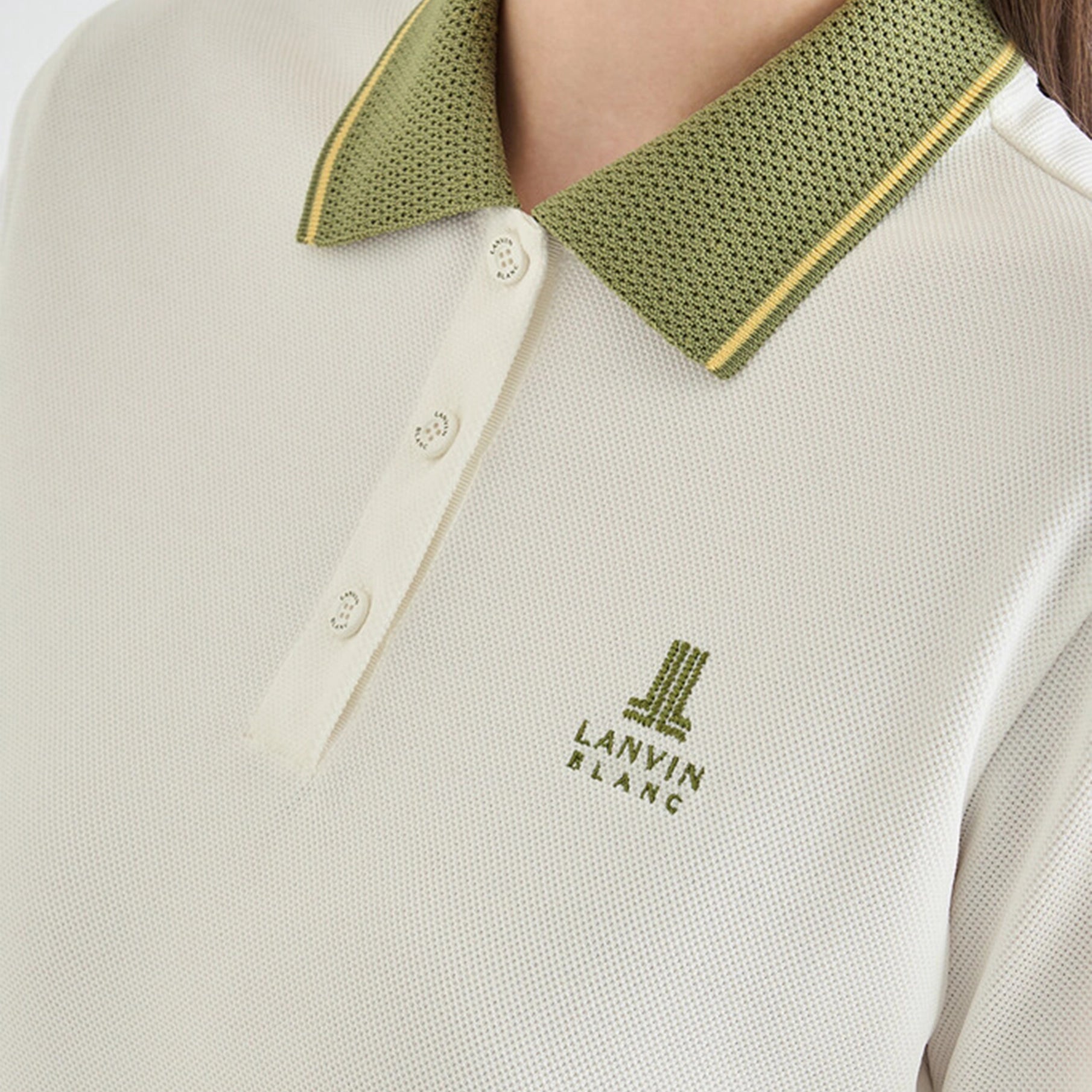 Close-up of a white polo shirt with green collar and Lanvin logo.