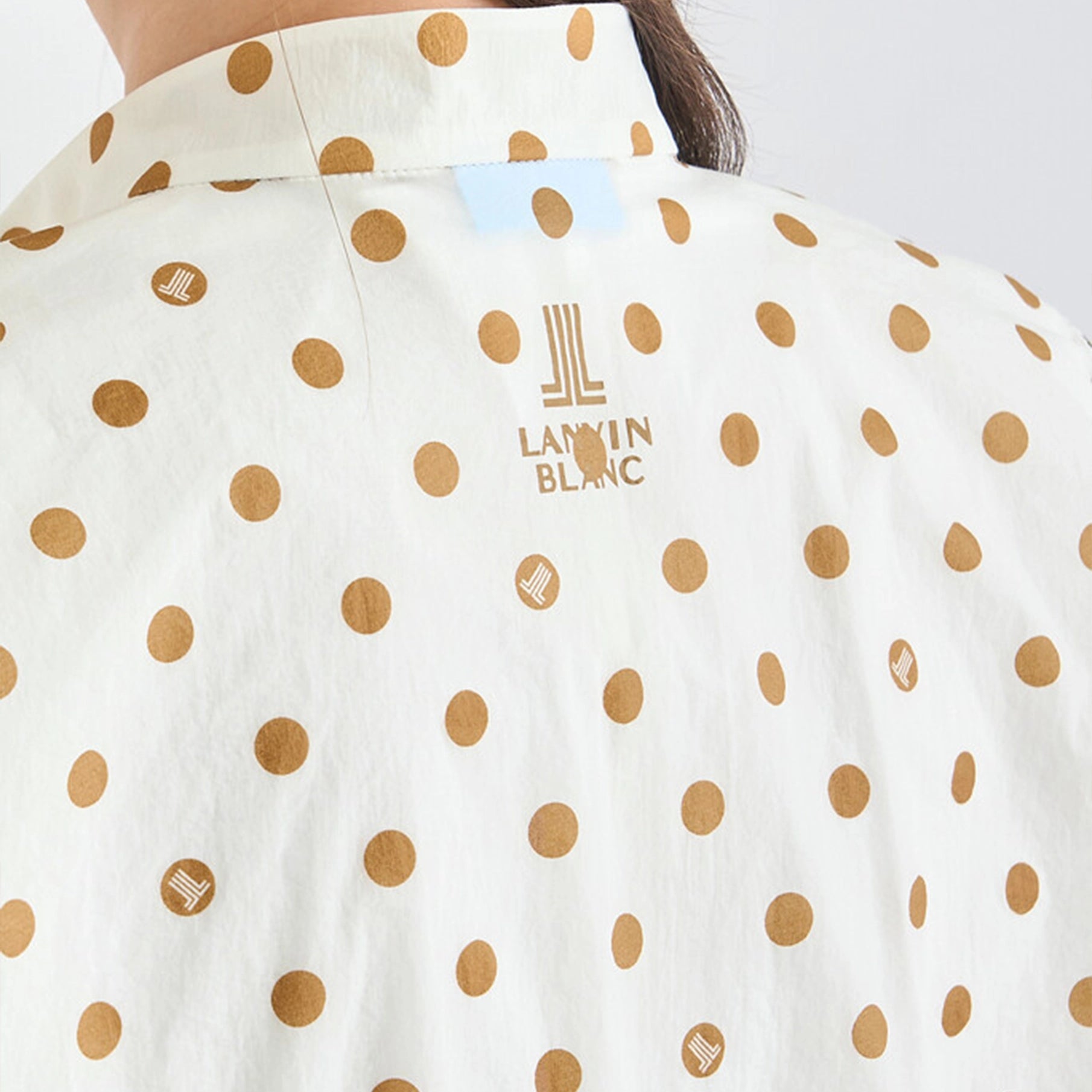 Close-up of a white shirt with gold polka dots and Lanvin Blanc logo.