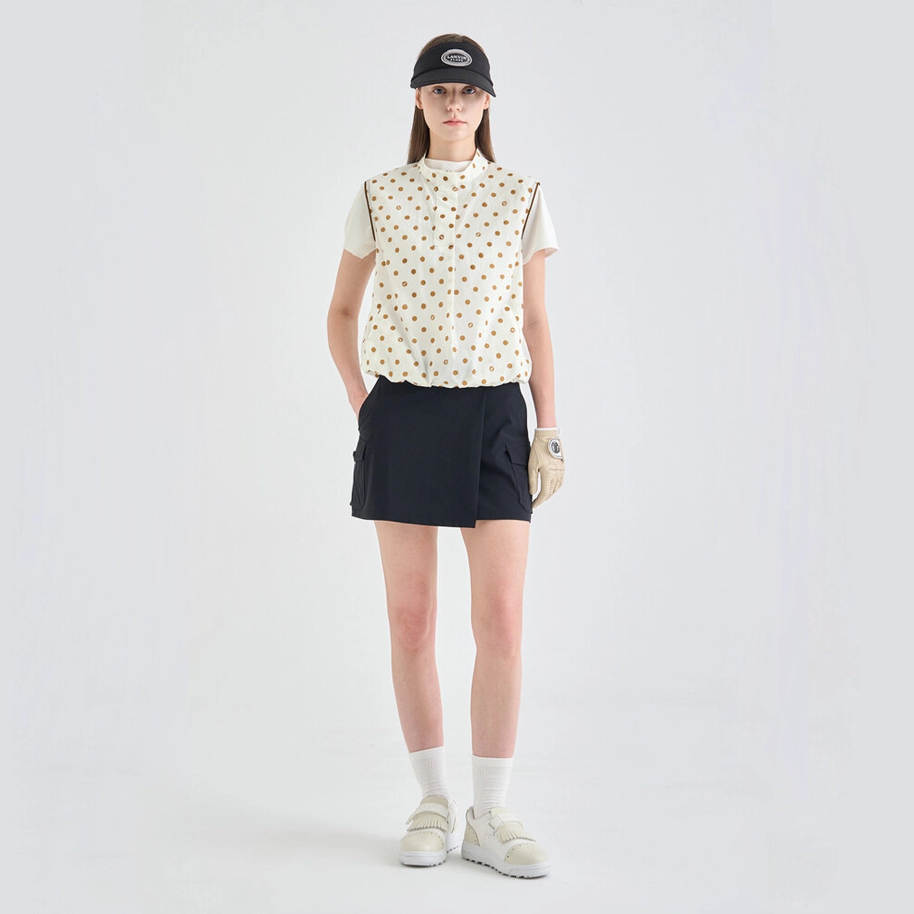 Person wearing a patterned shirt, black shorts, white socks, and sneakers on a light gray background