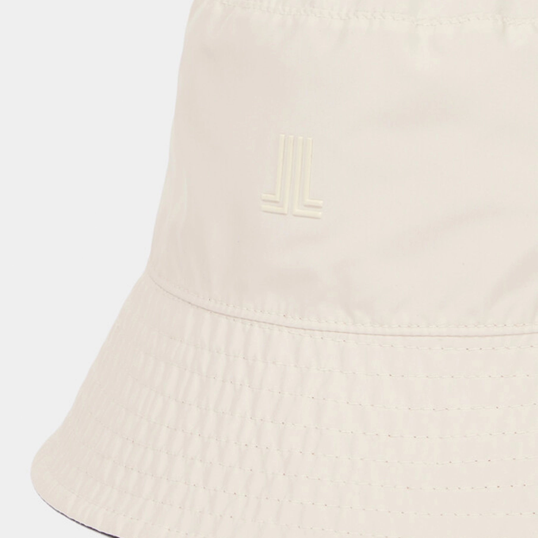 Close-up of a beige bucket hat with a brand logo on a white background