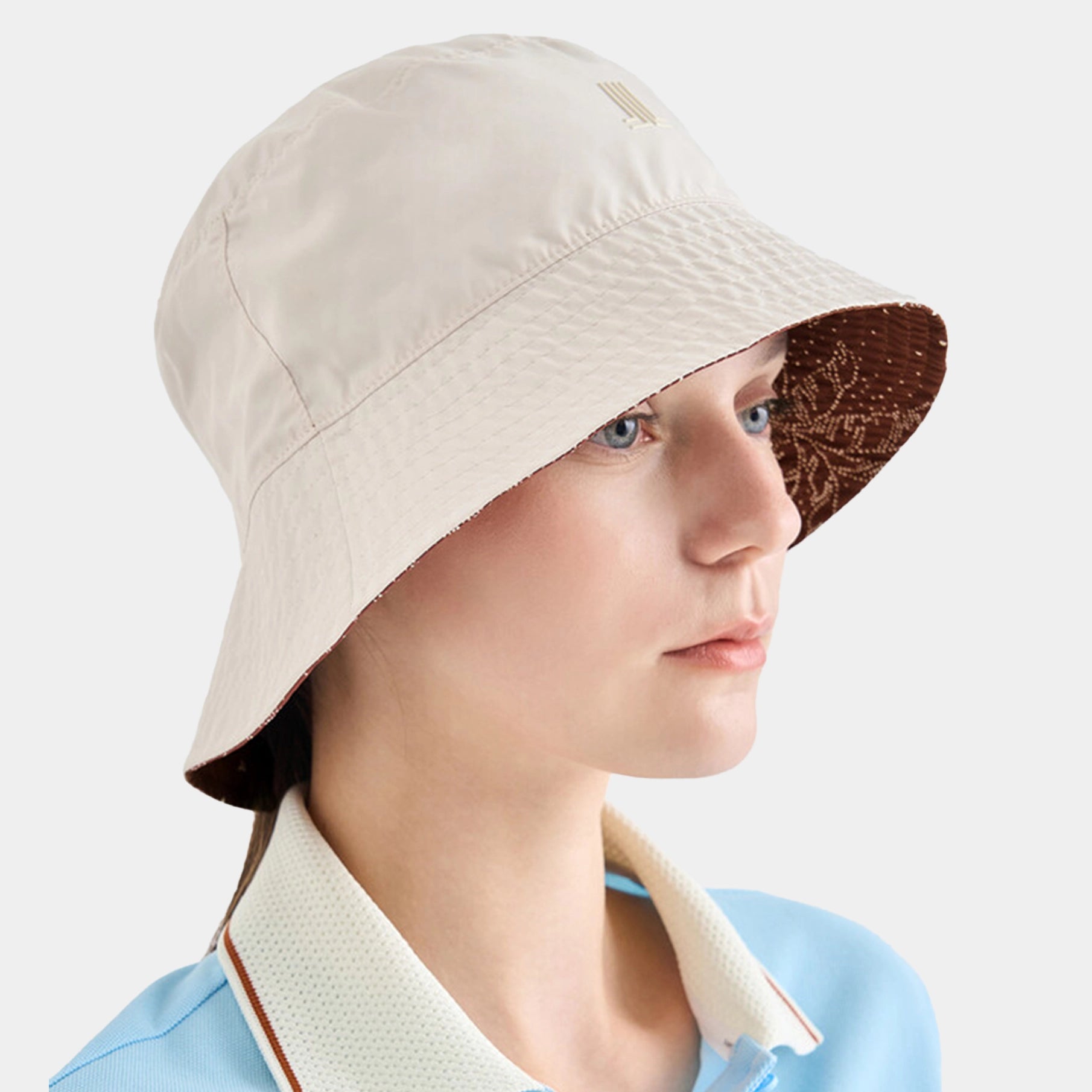 Person wearing a beige bucket hat with a brown interior on a white background