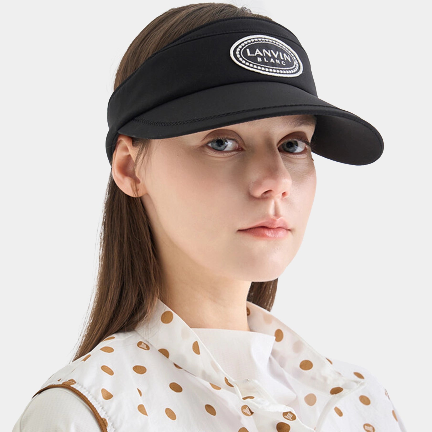 Woman wearing a black visor with a brand logo on a white background