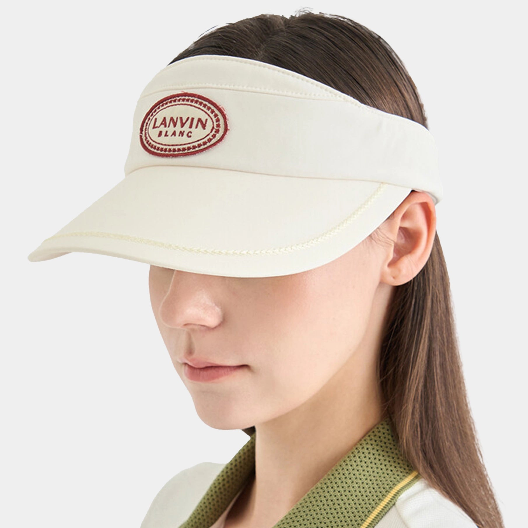 Person wearing a cream visor with a brand logo on a white background