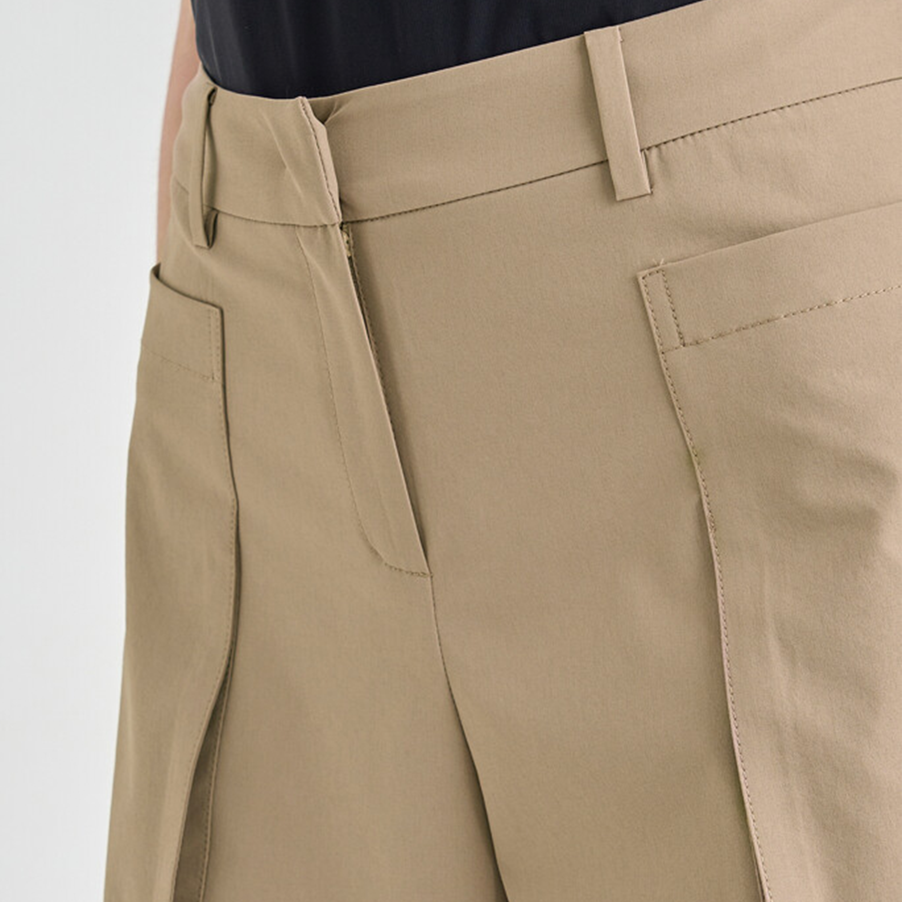 Close-up of beige shorts with a plain background