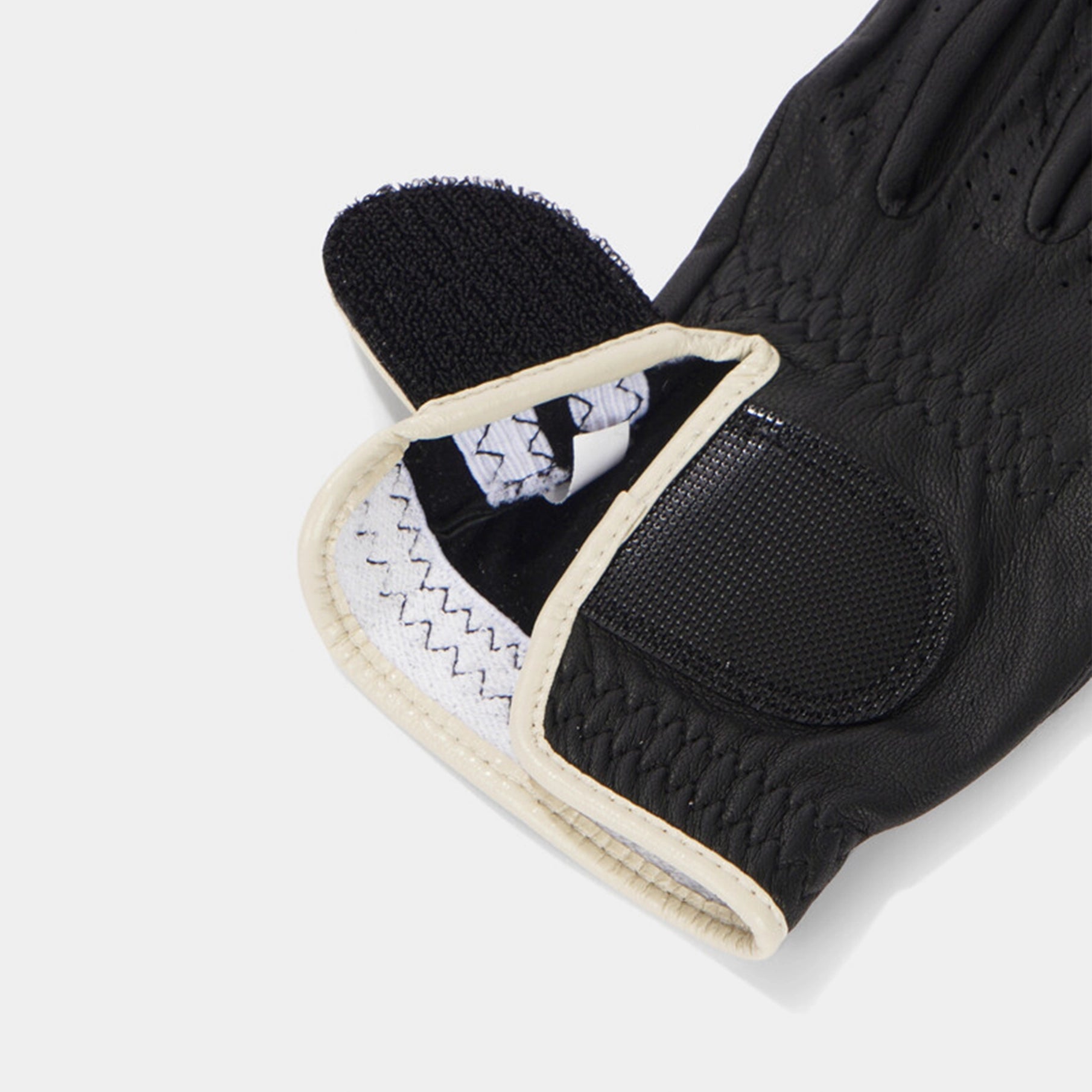Black glove with textured palm and white stitching on a light gray background