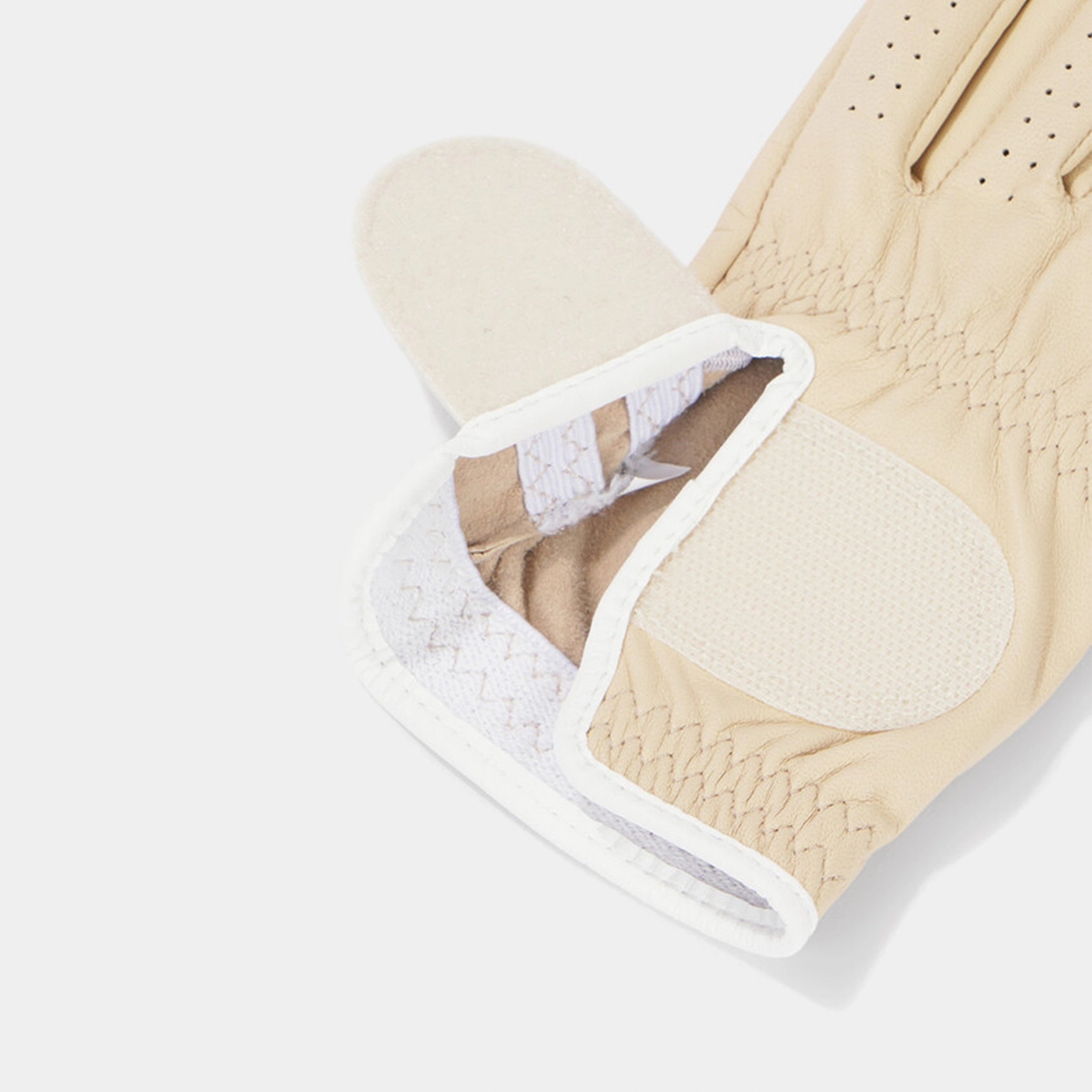 Beige golf glove with textured surface and white lining on a light gray background