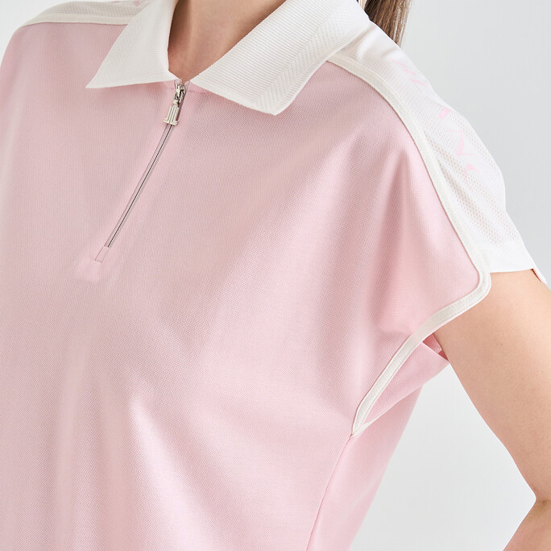 Pink polo shirt with white collar and zipper on a light gray background